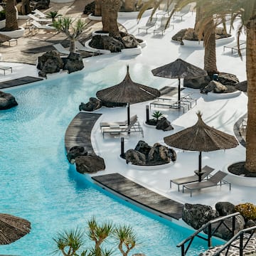 a pool with umbrellas and chairs and palm trees
