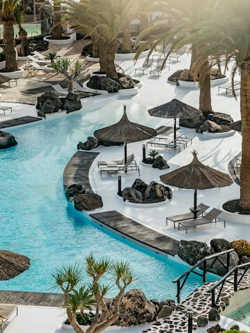 a pool with umbrellas and chairs and palm trees