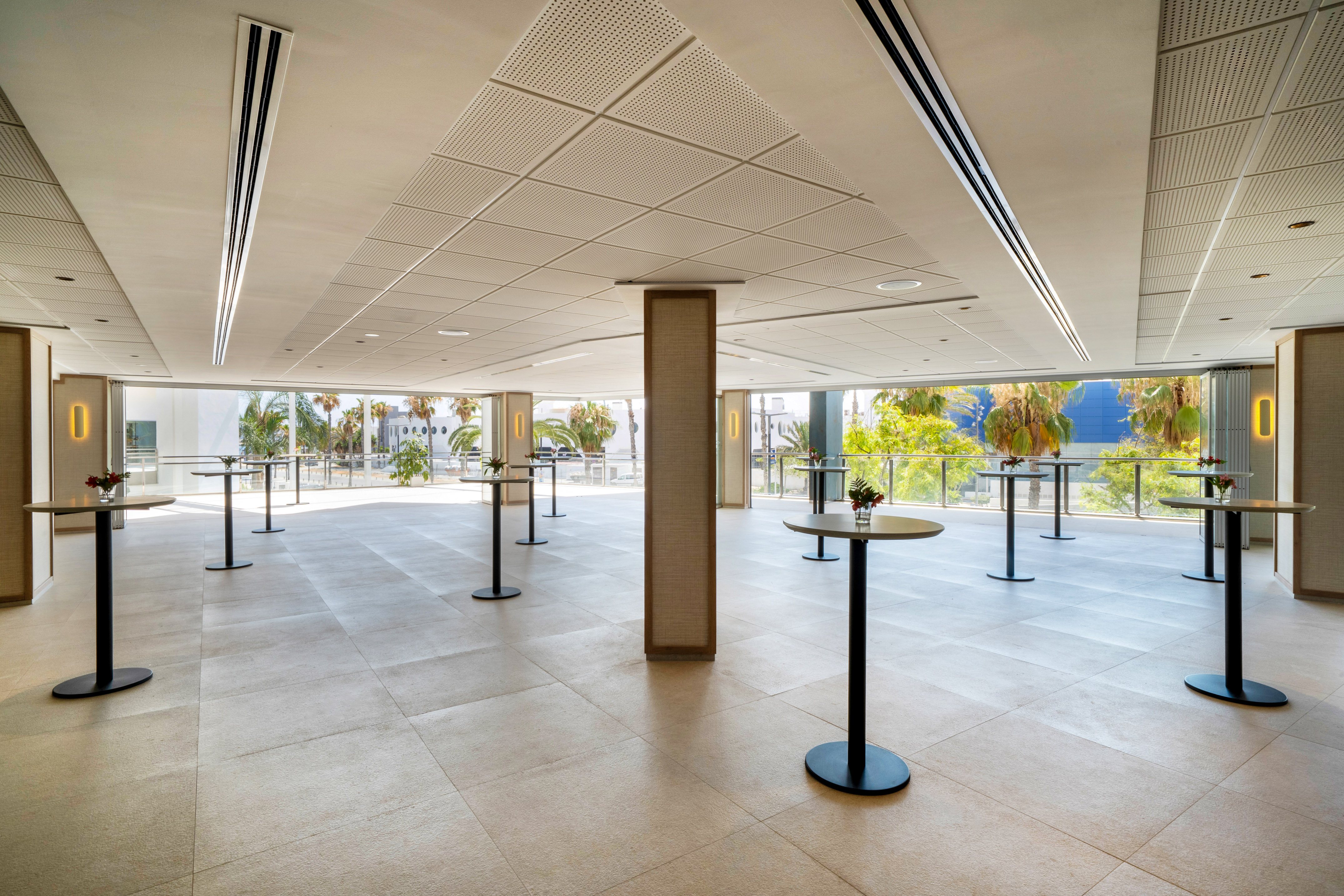 Modern event space with high-top tables and large windows with palm trees.