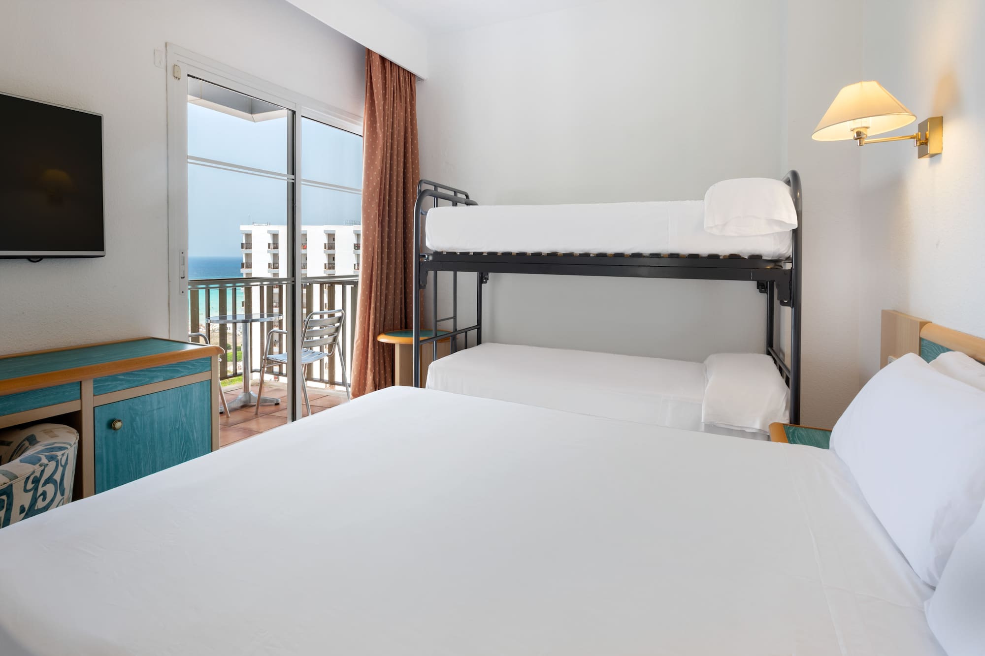 a bunk beds in a room with a balcony overlooking the ocean