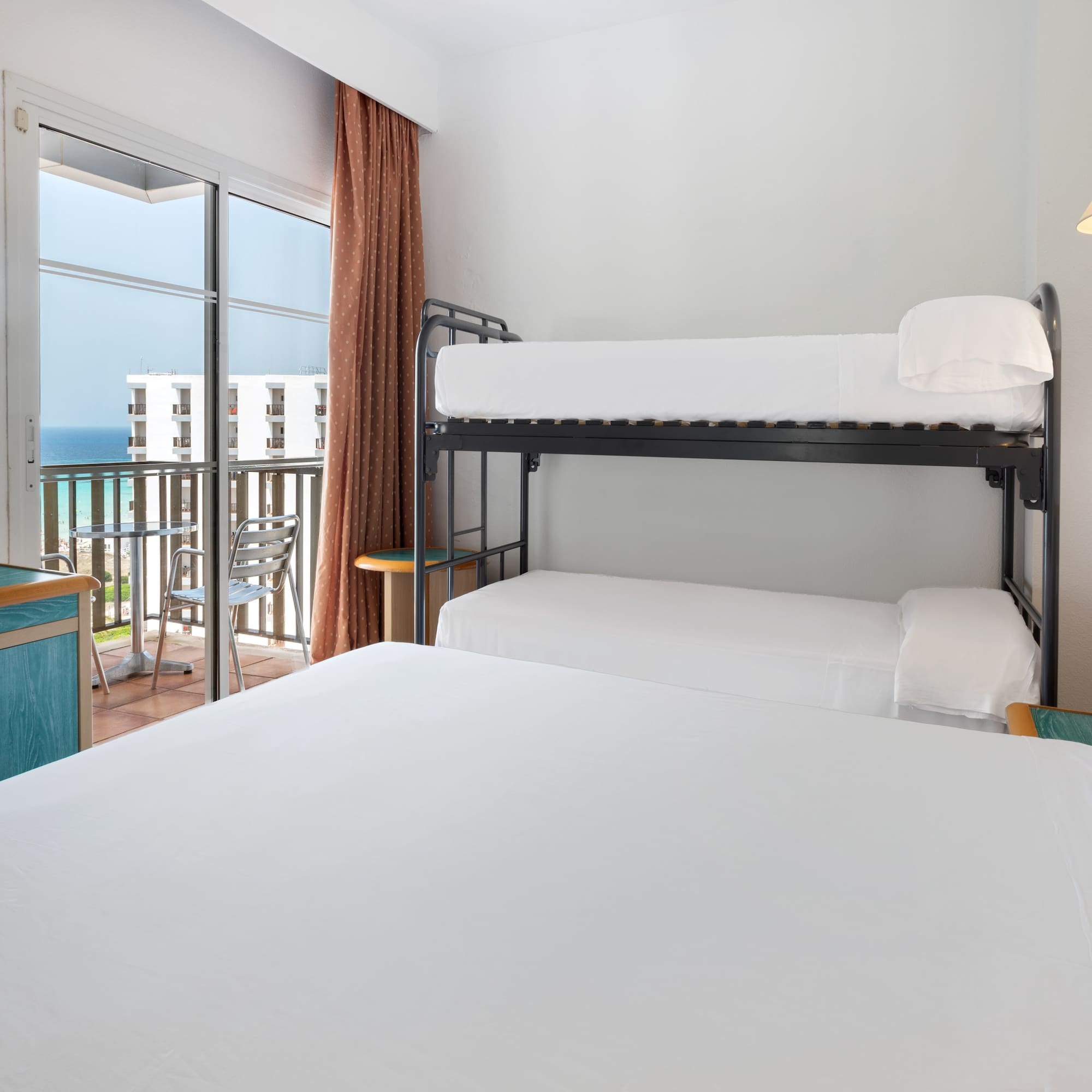 a bunk beds in a room with a balcony overlooking the ocean