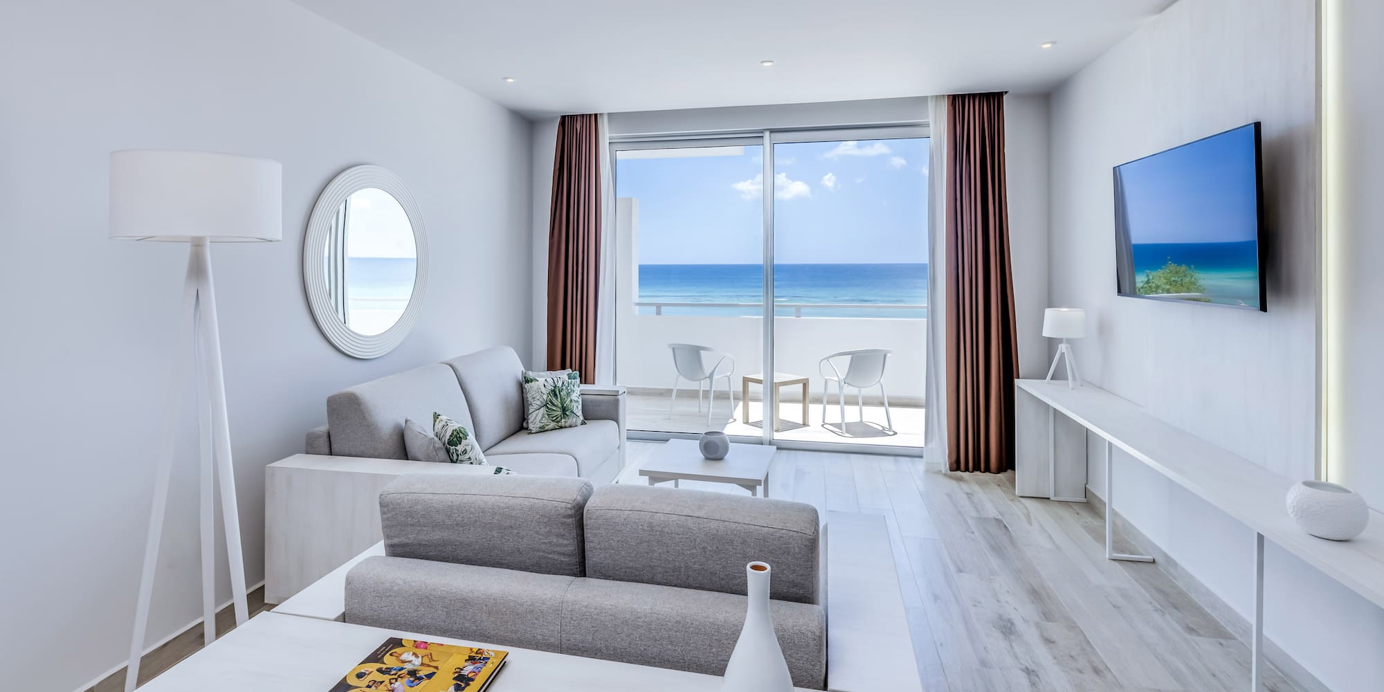 a living room with a television and a view of the ocean