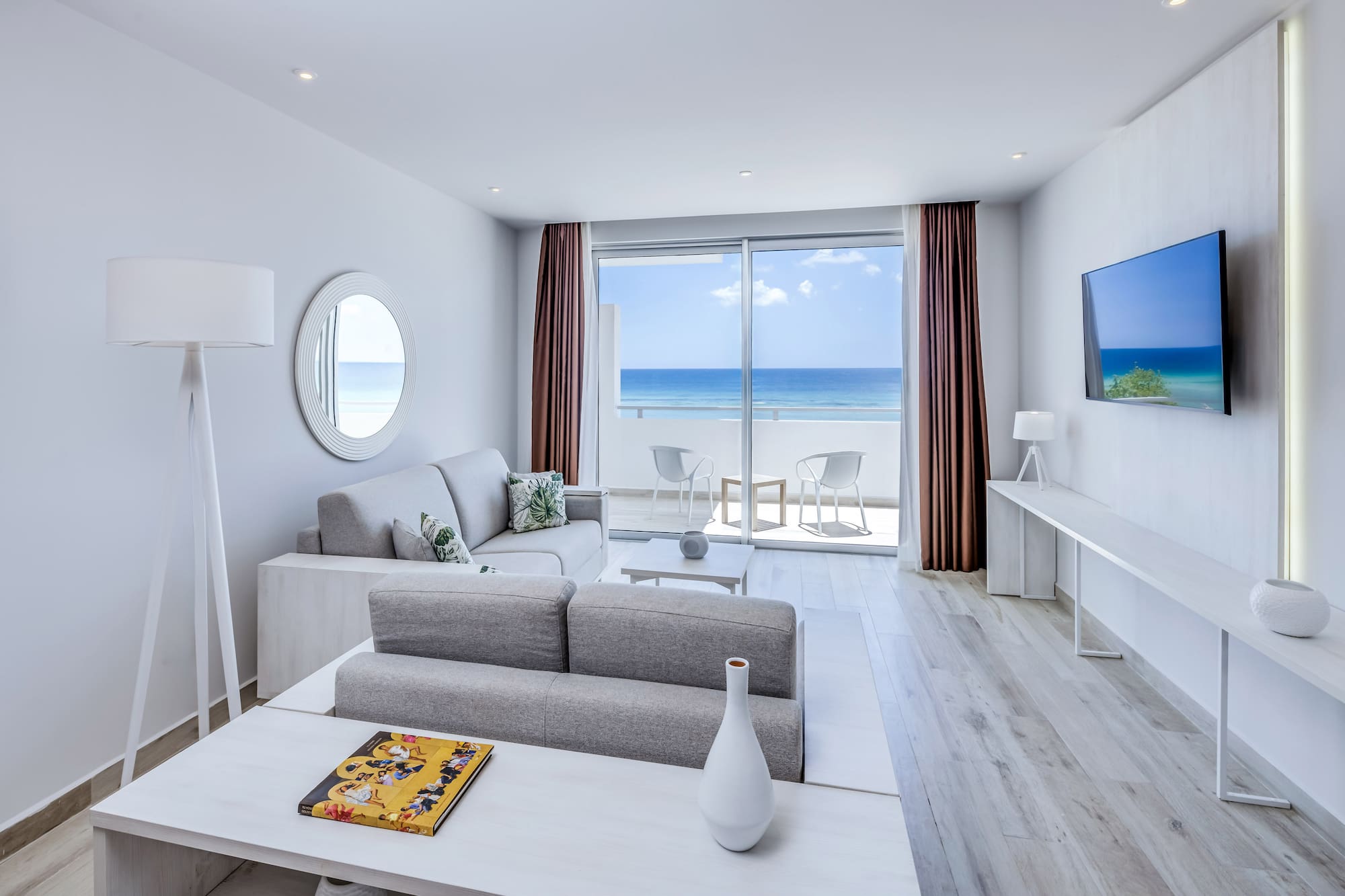 a living room with a television and a view of the ocean