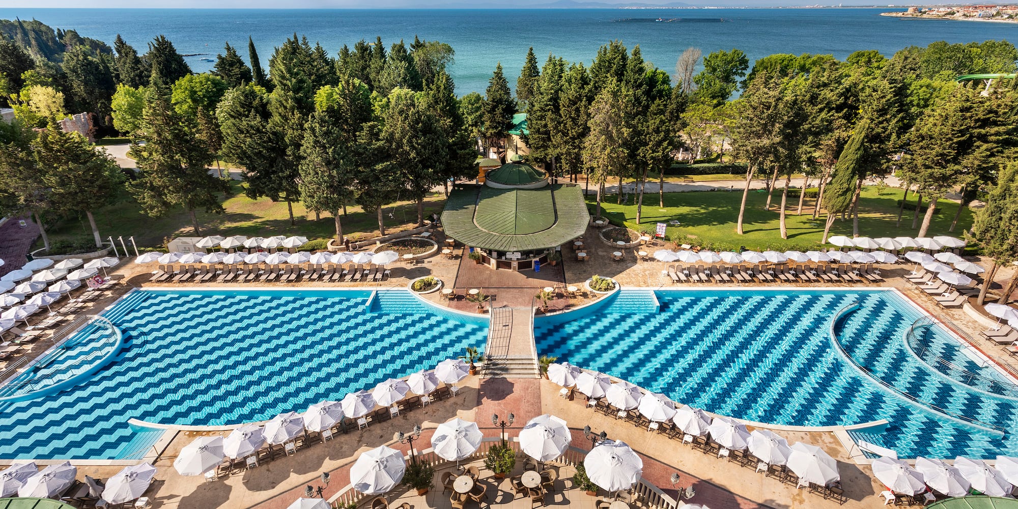 a pool with umbrellas and chairs and trees