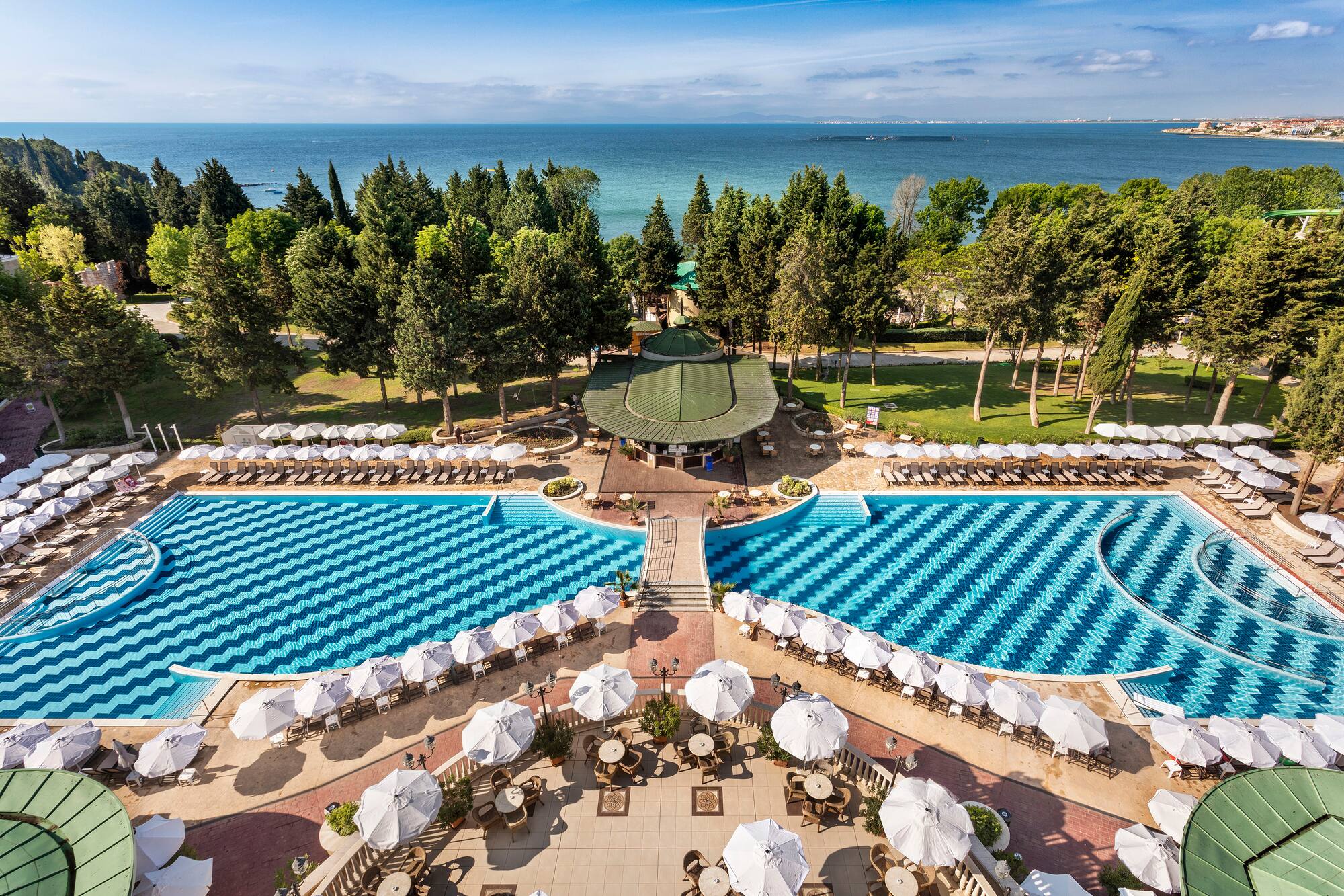 a pool with umbrellas and chairs and trees