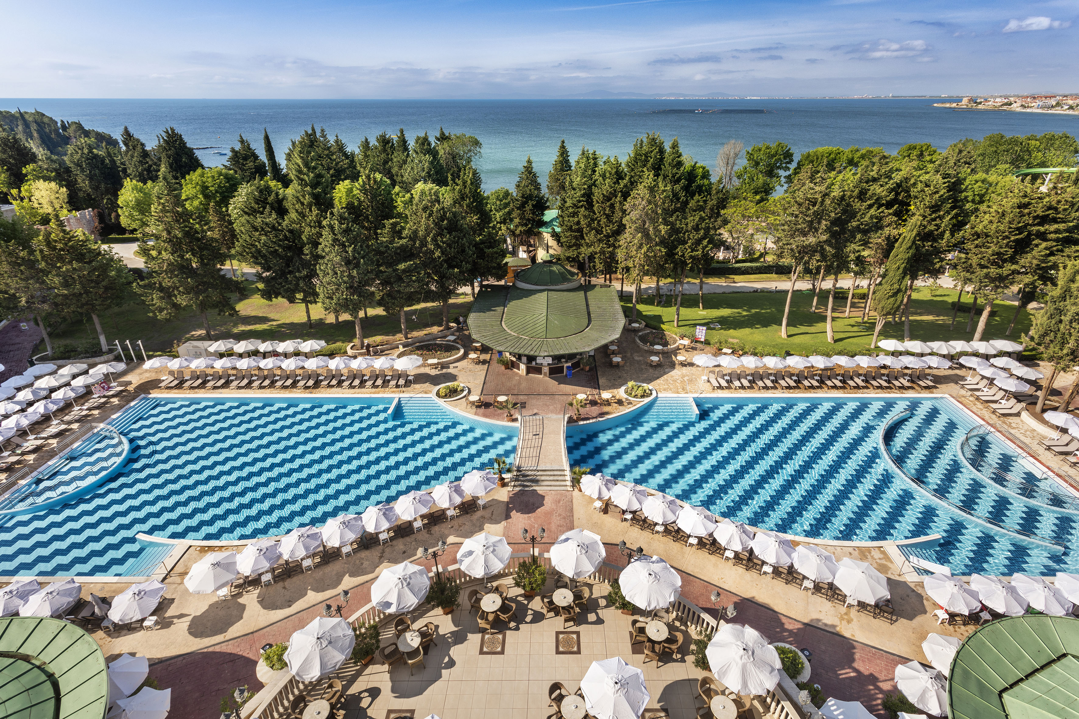 a pool with umbrellas and chairs and trees