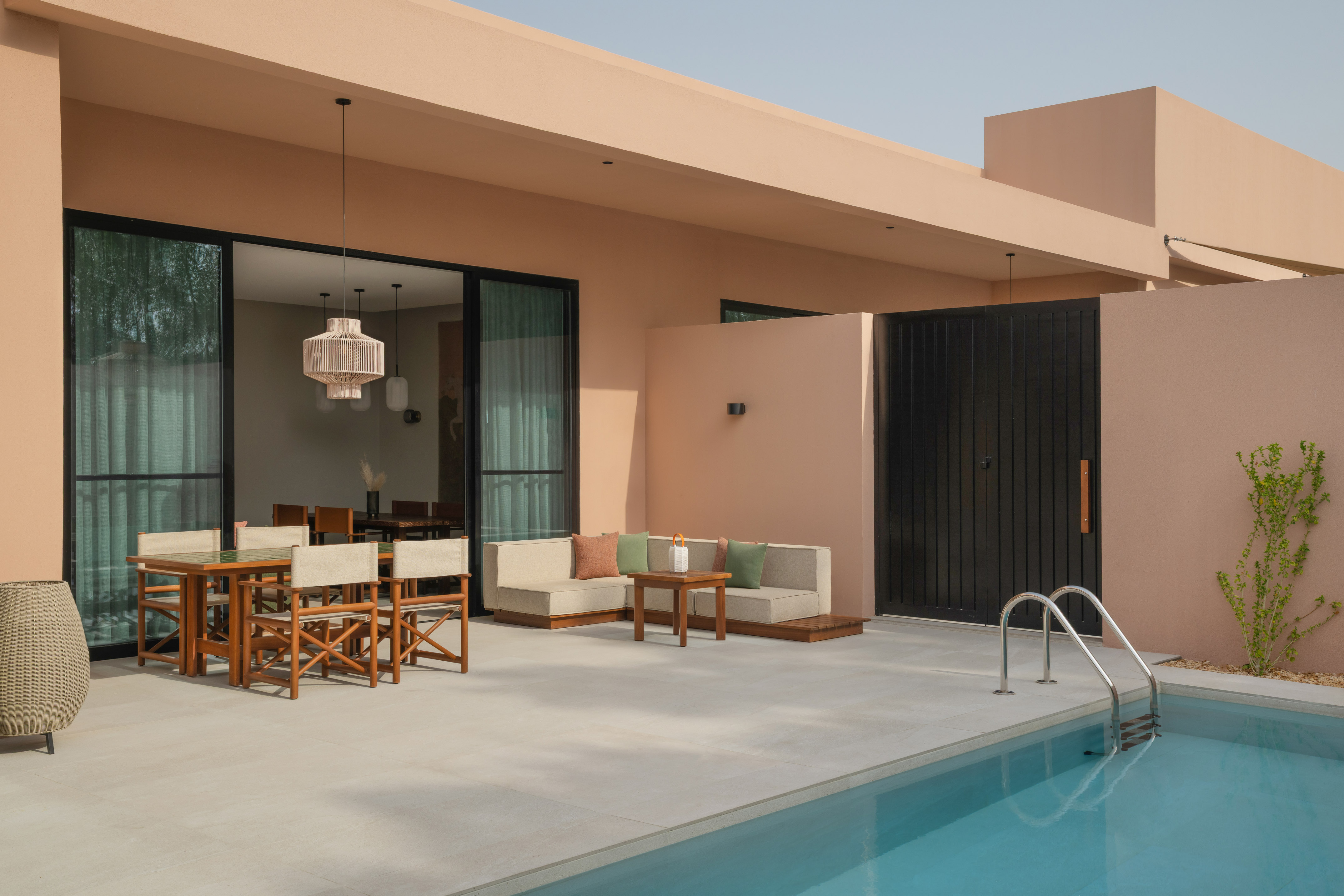 Modern peach villa with pool, patio, outdoor dining, and lounge.