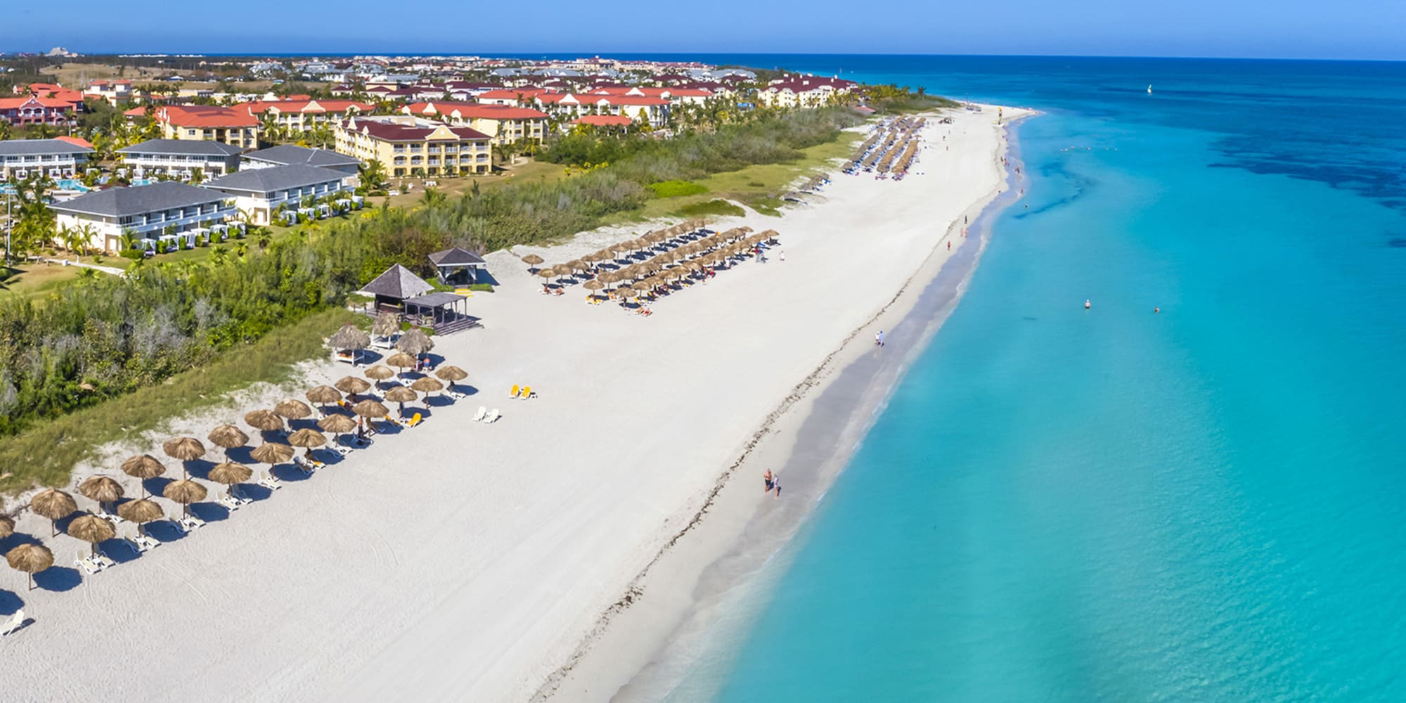 a beach with umbrellas and buildings