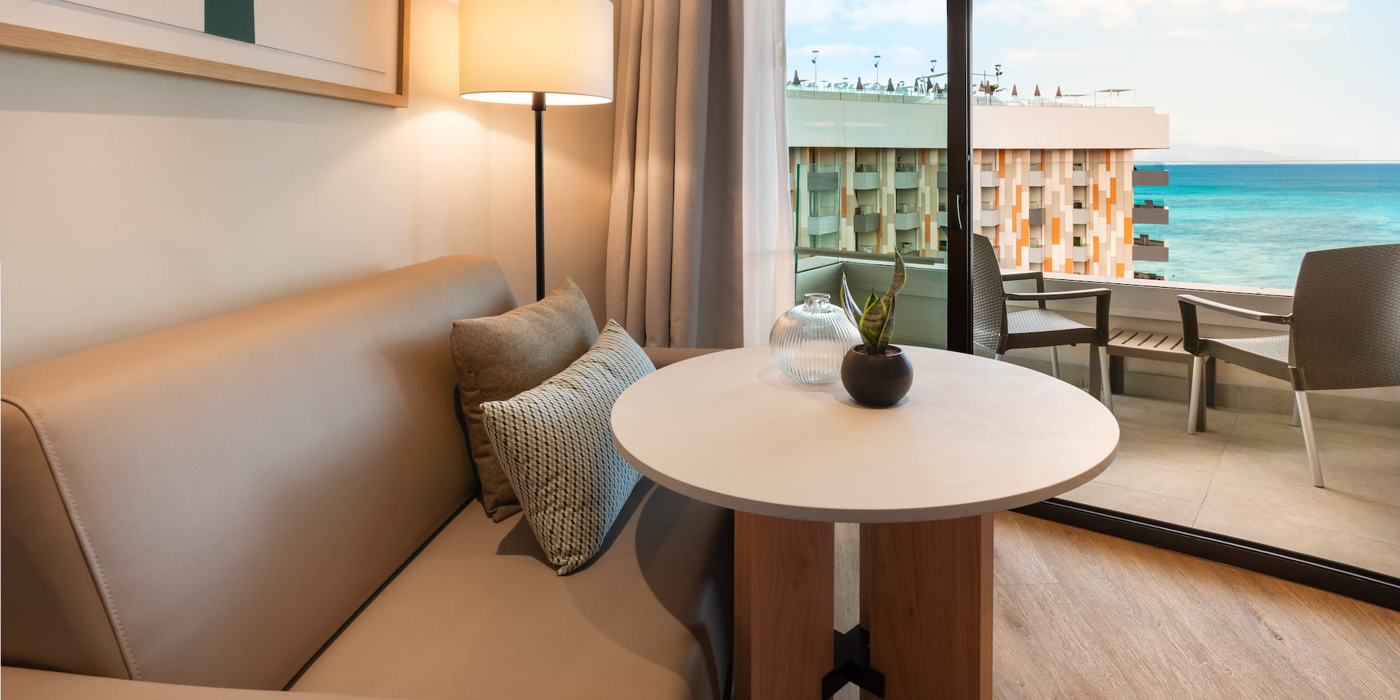 a couch and table with a lamp in front of a glass door