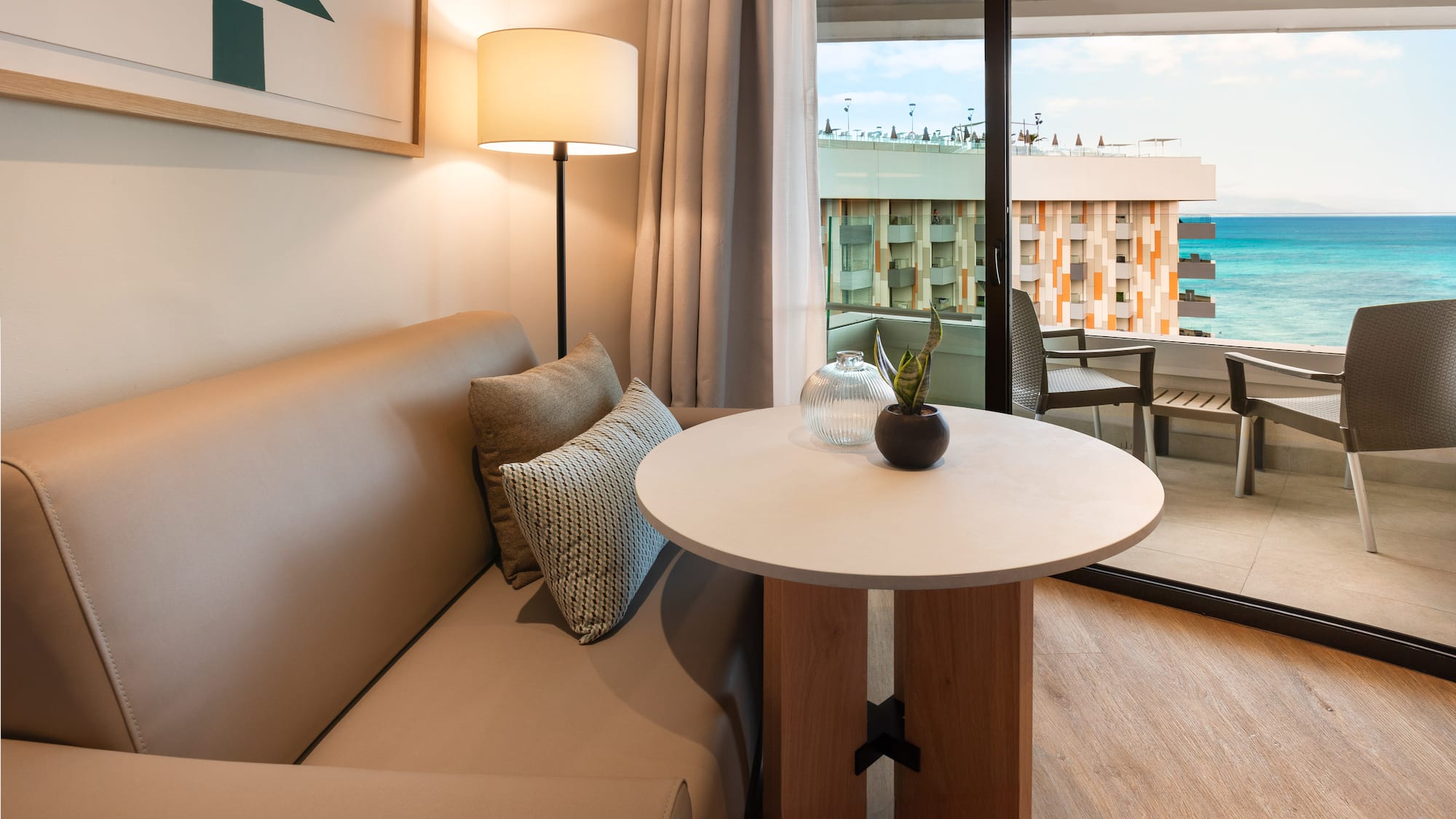a couch and table with a lamp in front of a glass door