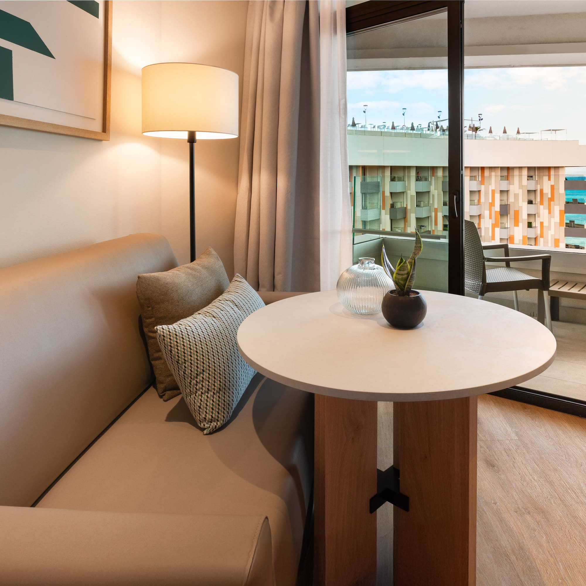 a couch and table with a lamp in front of a glass door