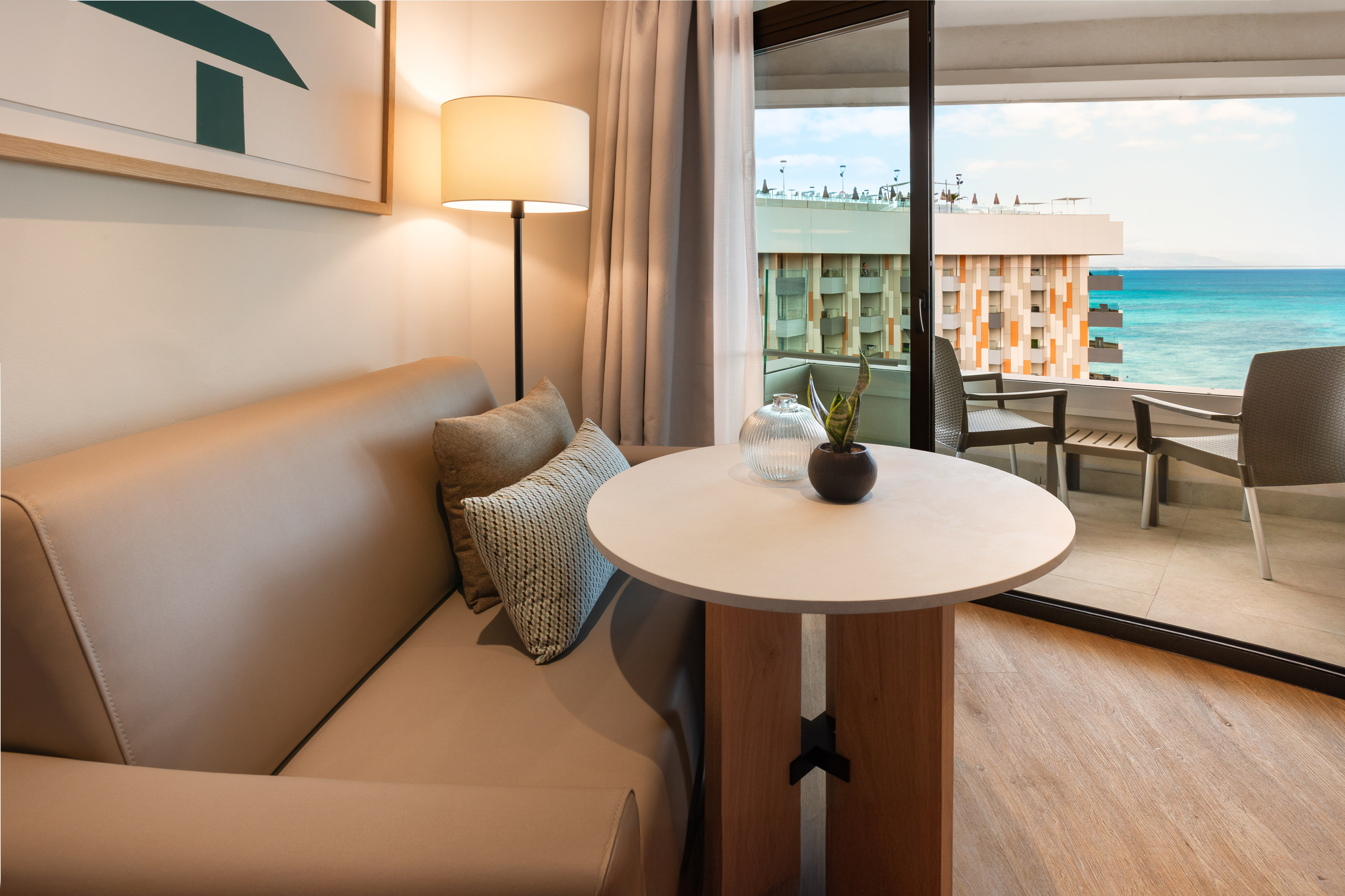 Modern hotel room lounge area with sea view balcony.