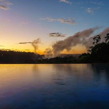 a body of water with trees and clouds in the sky