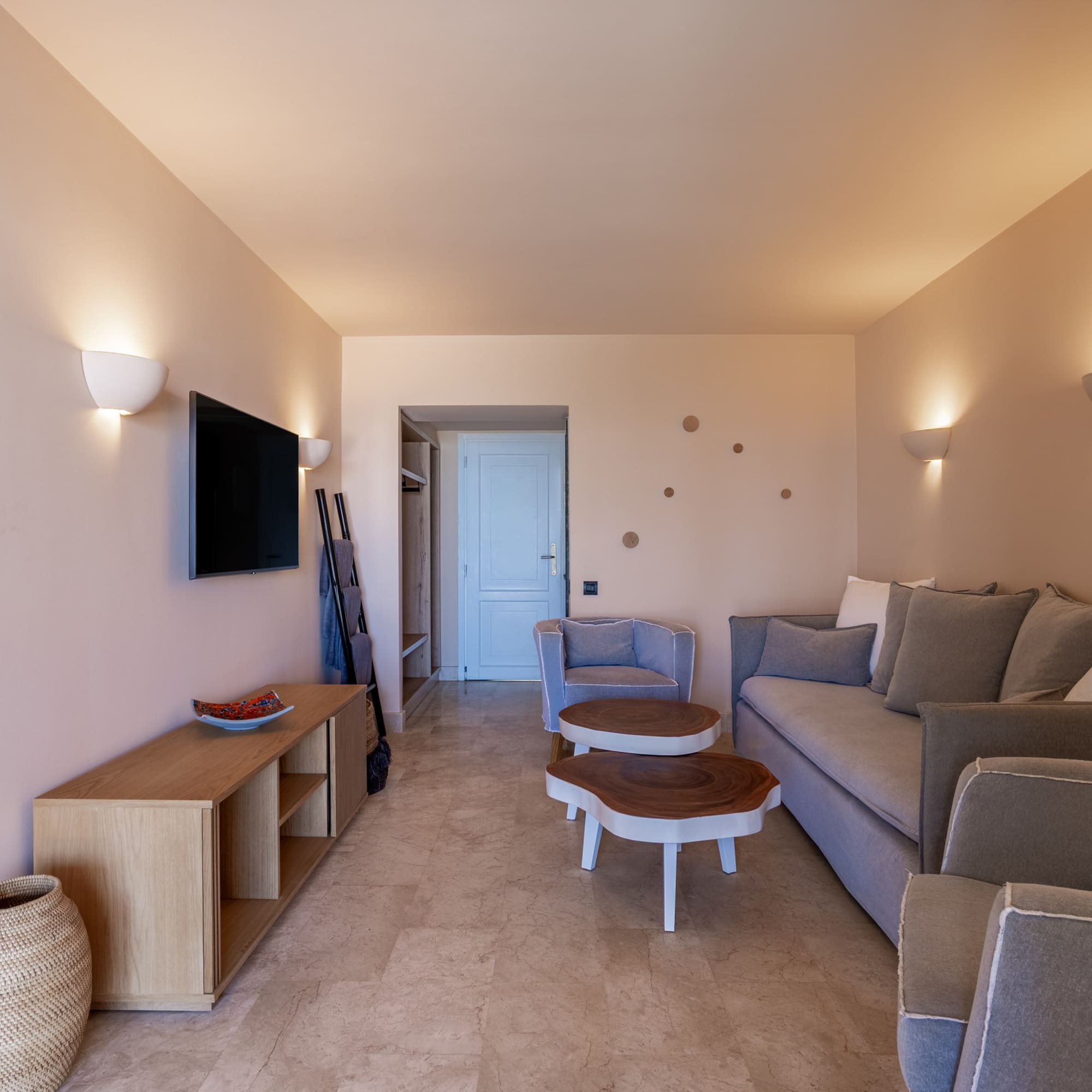 Modern living room with neutral beige walls, grey sofa, and wooden coffee tables.