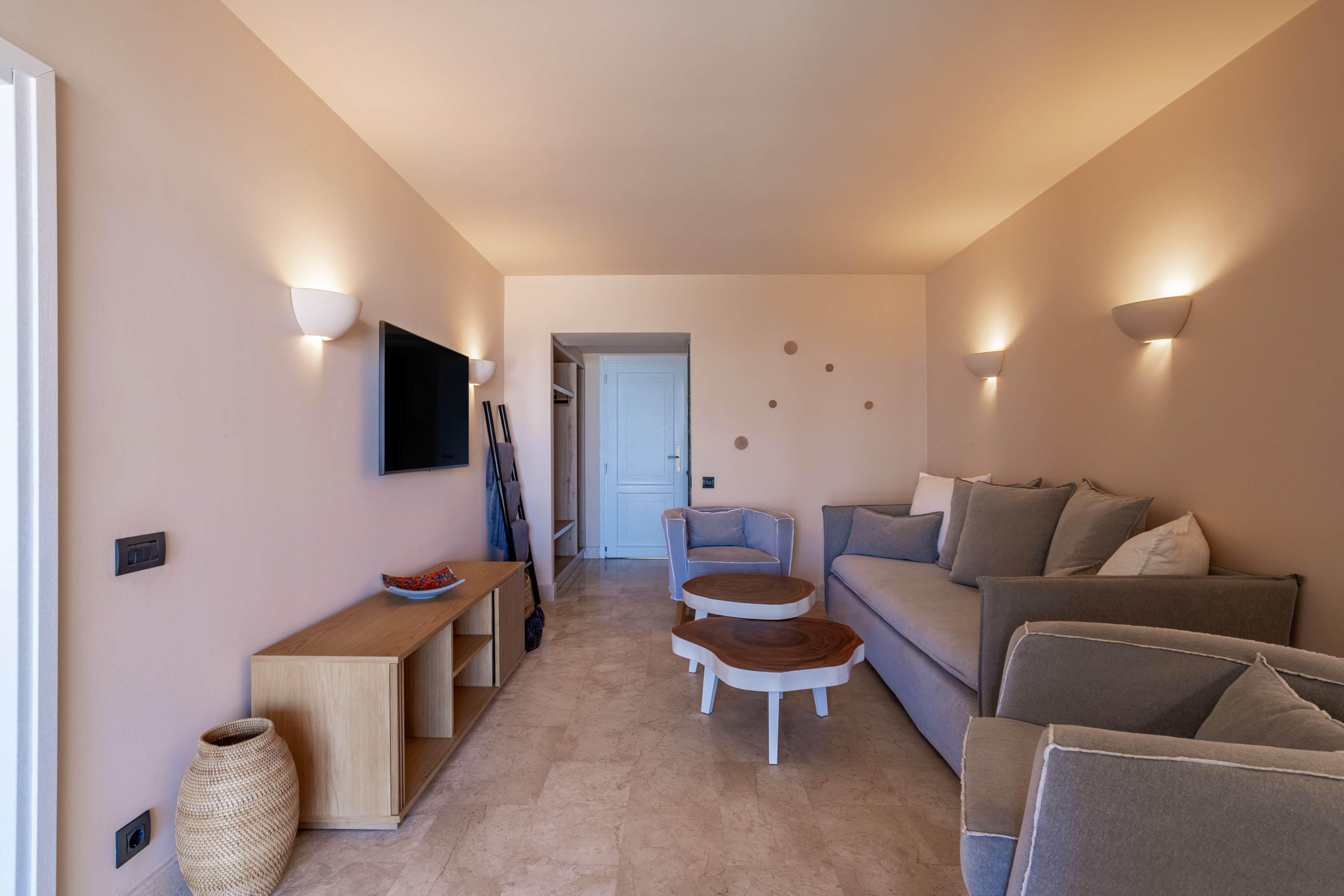 Modern living room with neutral beige walls, grey sofa, and wooden coffee tables.