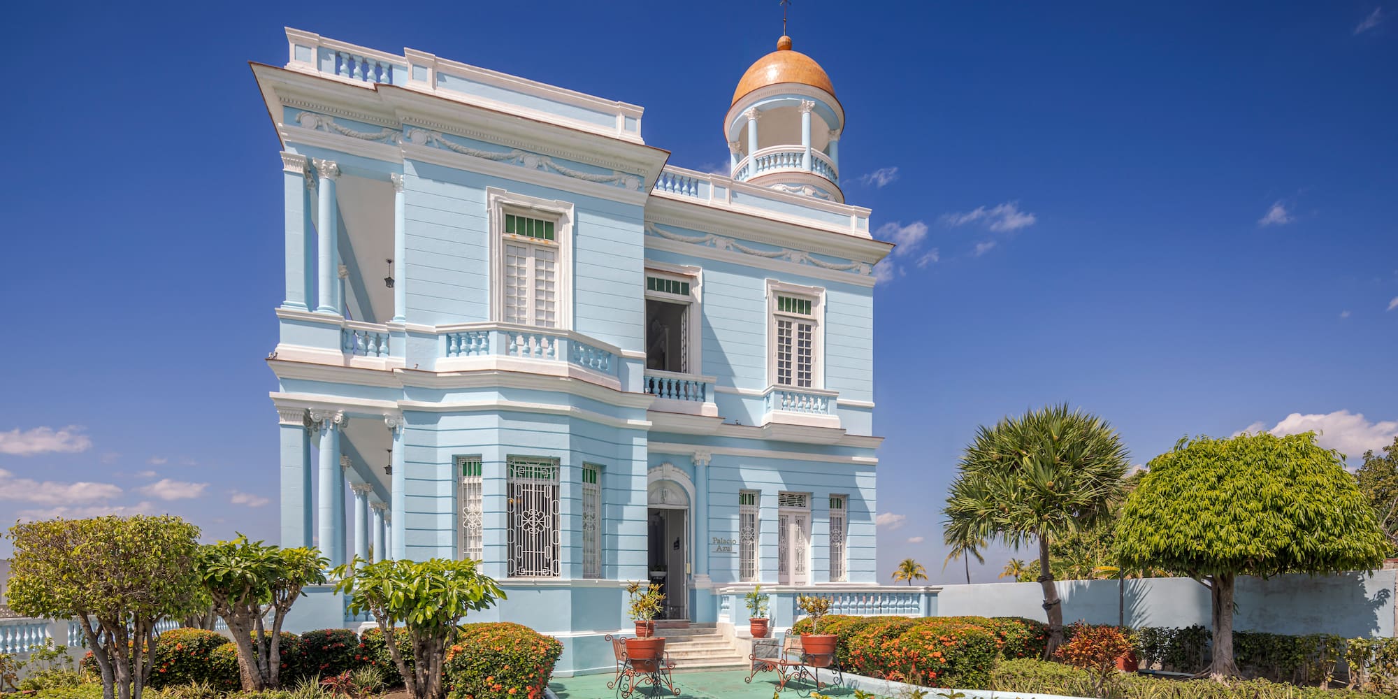 a blue building with a garden and a walkway