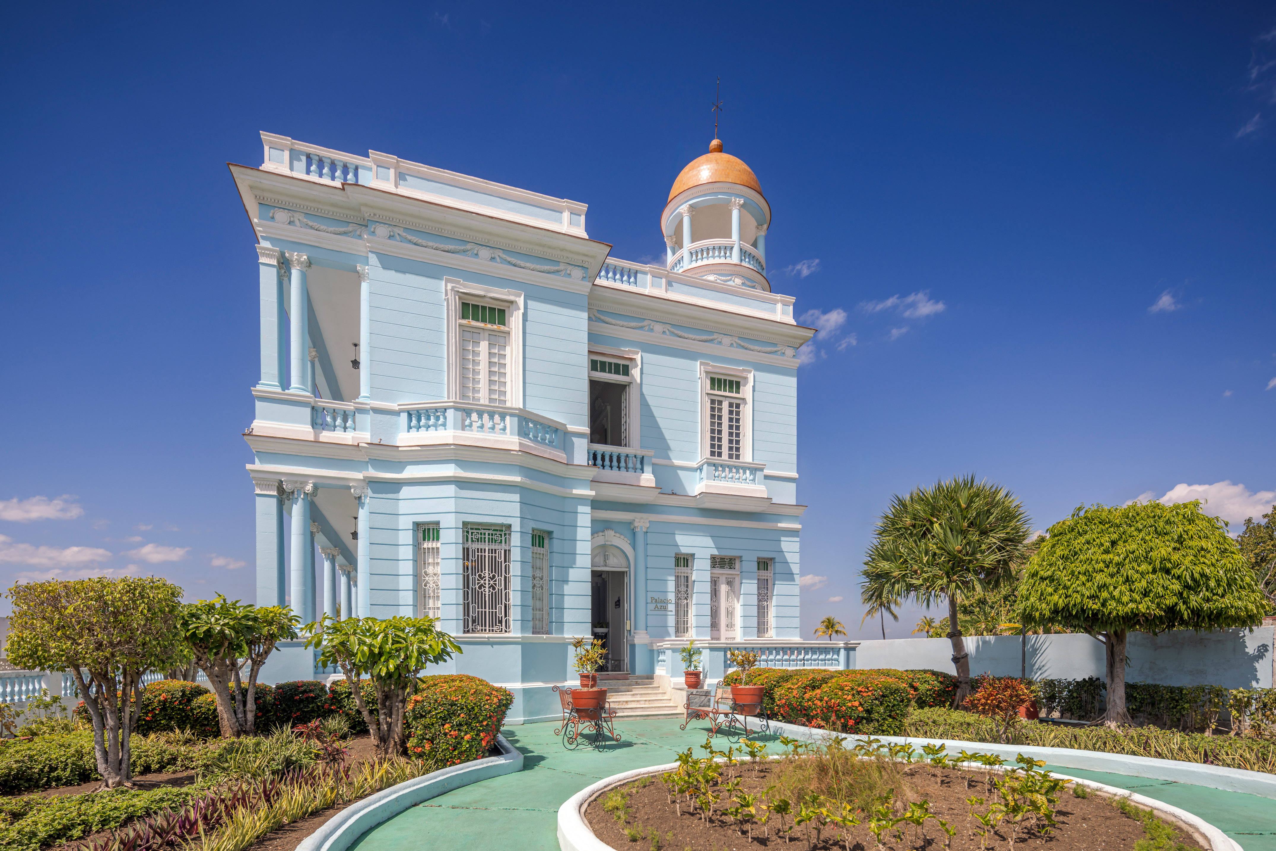 a blue building with a garden and a walkway