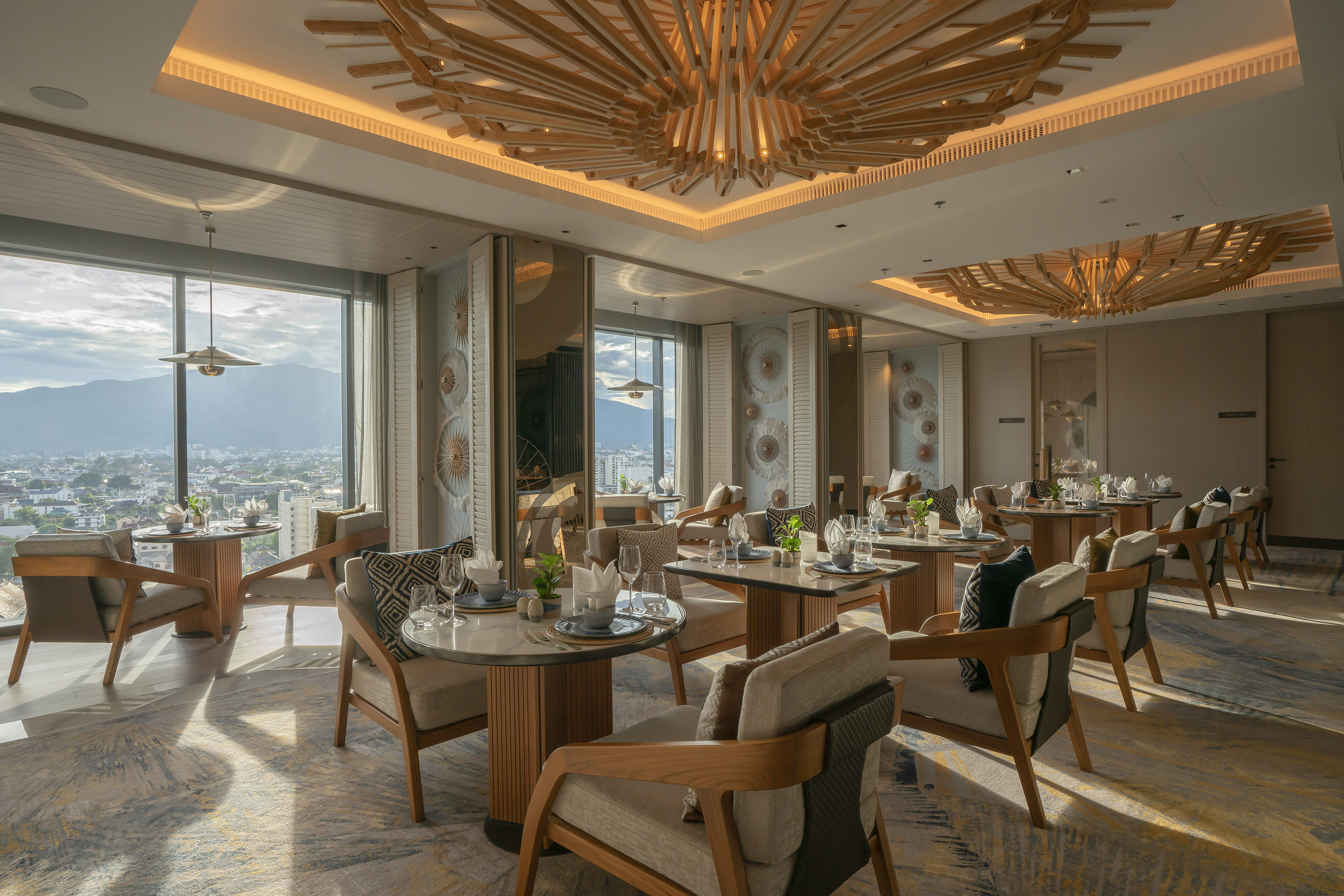 Modern luxury restaurant with city and mountain view, intricate wooden ceiling.