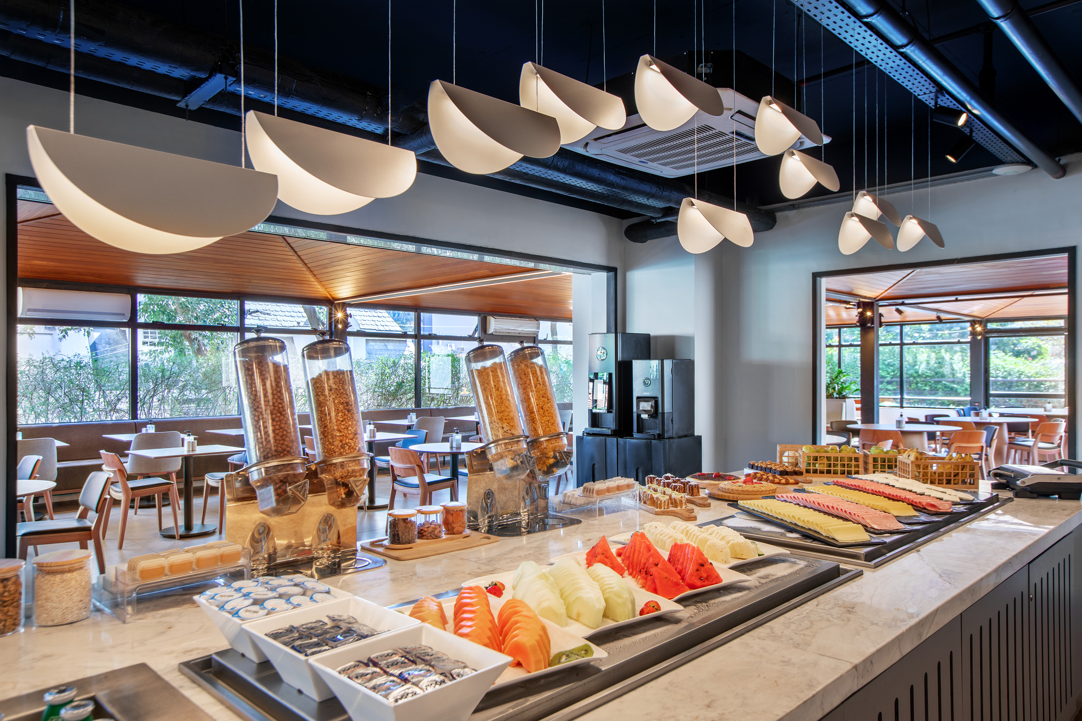 Modern hotel breakfast buffet with fresh fruit, cereals, and cold cuts.