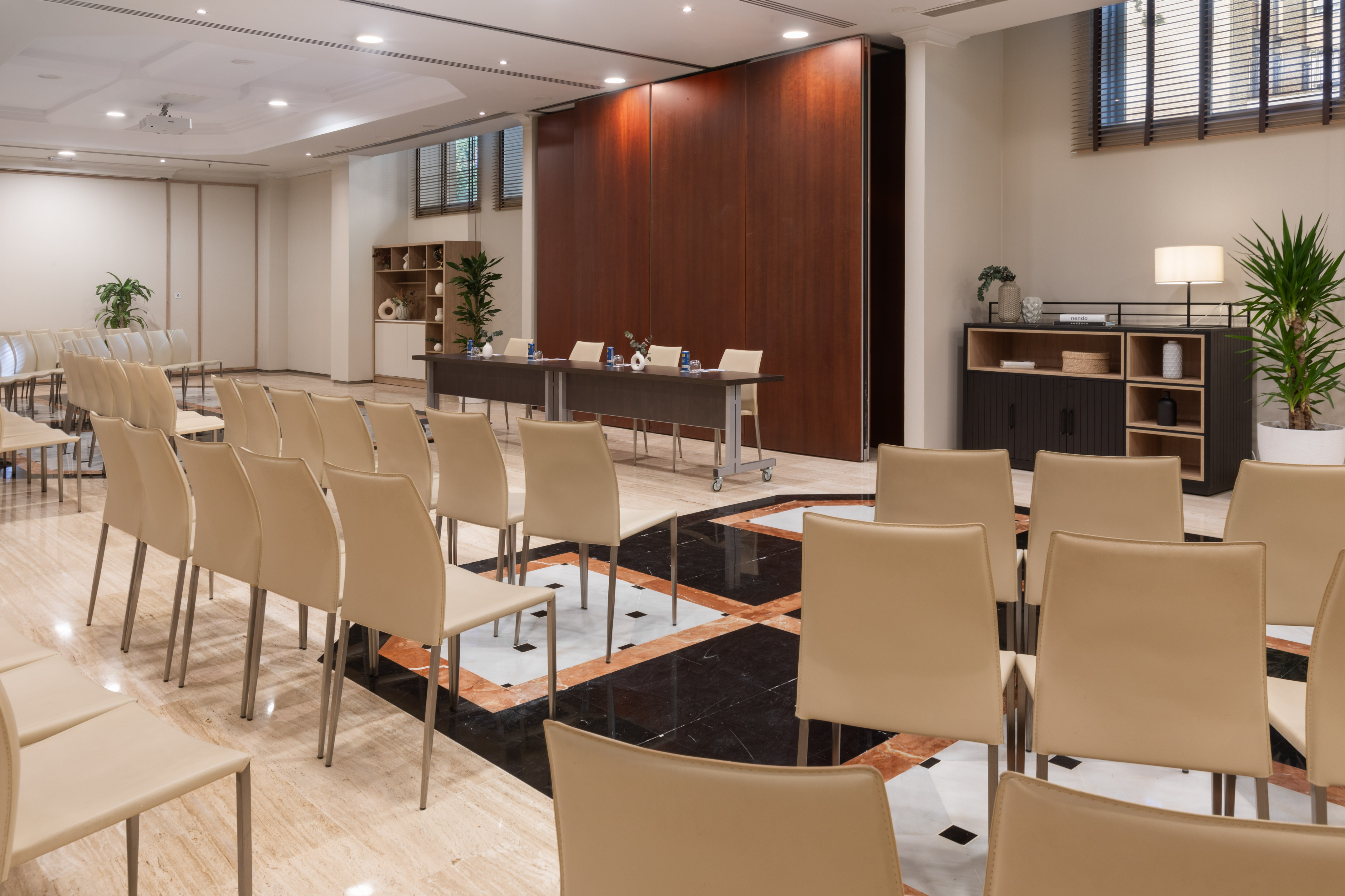 Modern conference room with empty chairs, presentation table, and wooden panels.
