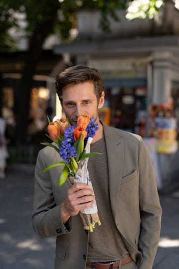a man smelling flowers