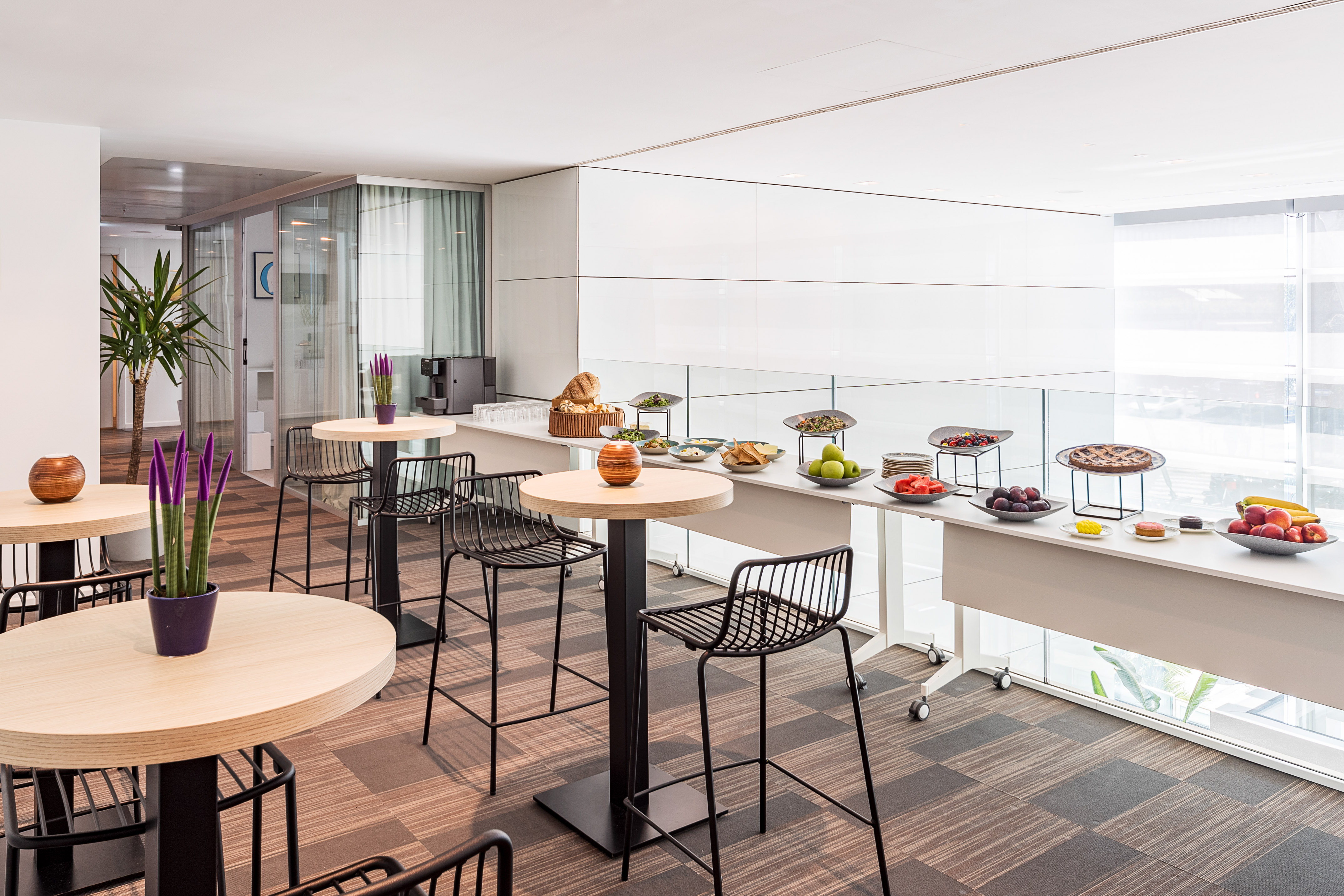Modern office catering buffet with high-top tables and fresh food selections.