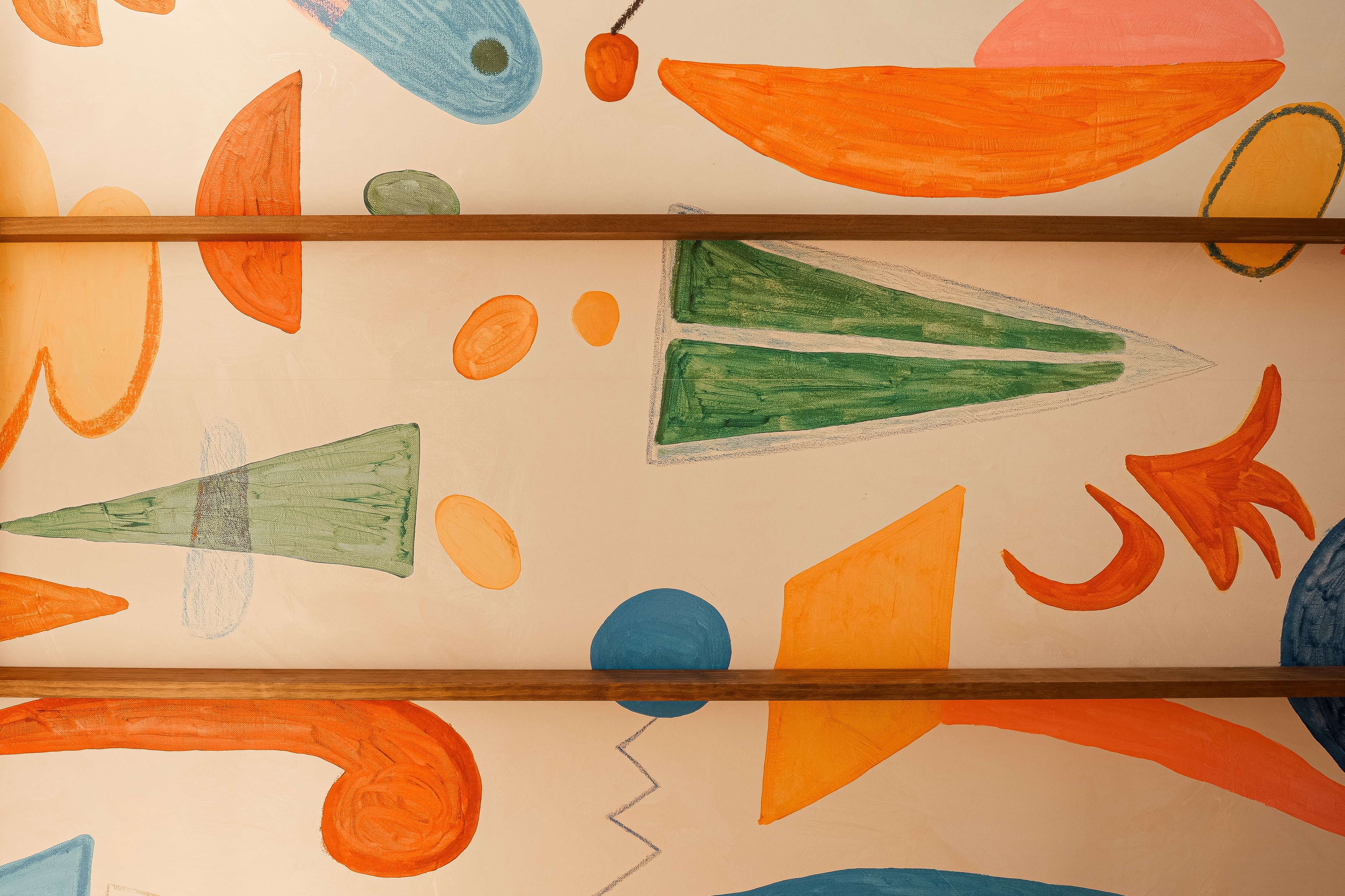 Colorful abstract wall mural with painted geometric shapes and wooden shelves.