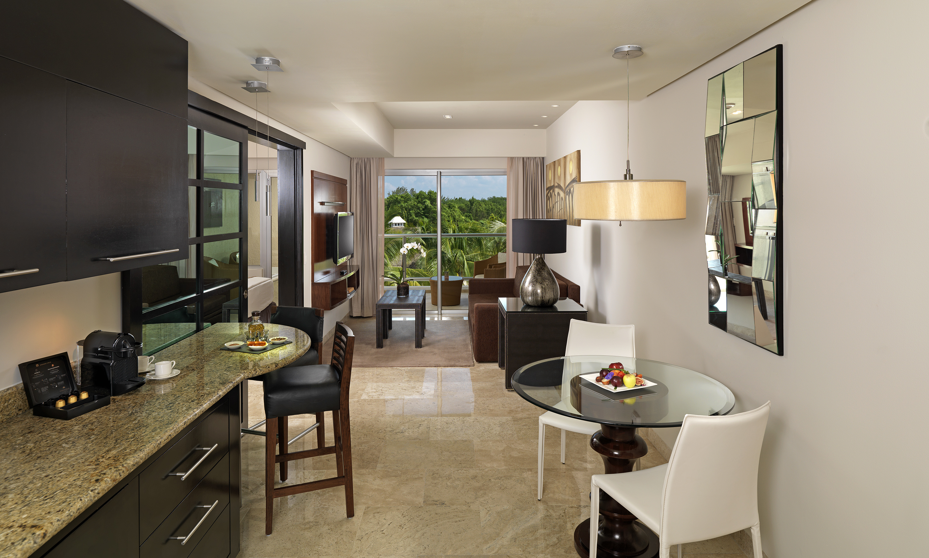 Modern suite with kitchen, living, dining areas and tropical balcony view.