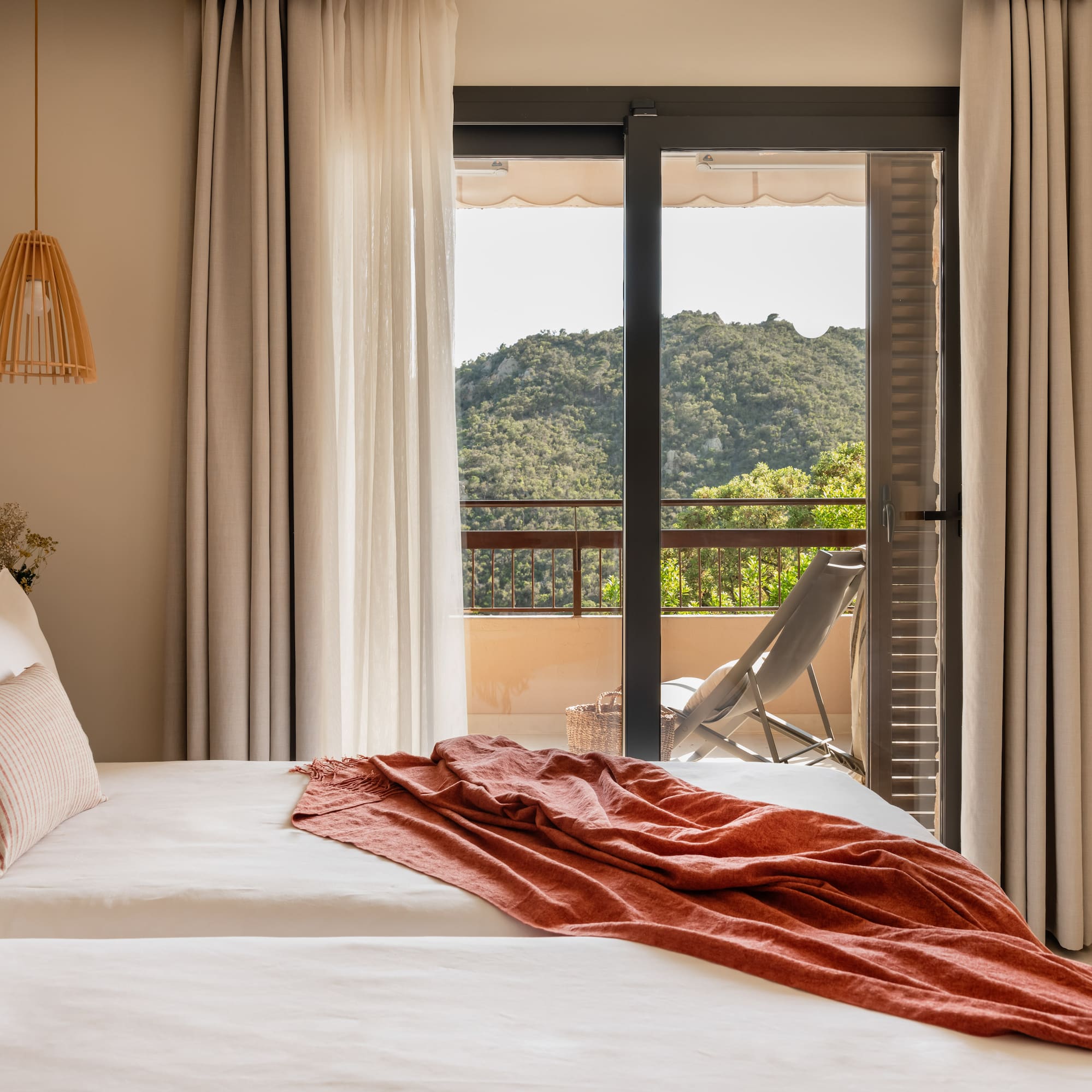 a bed with a red blanket and a chair outside