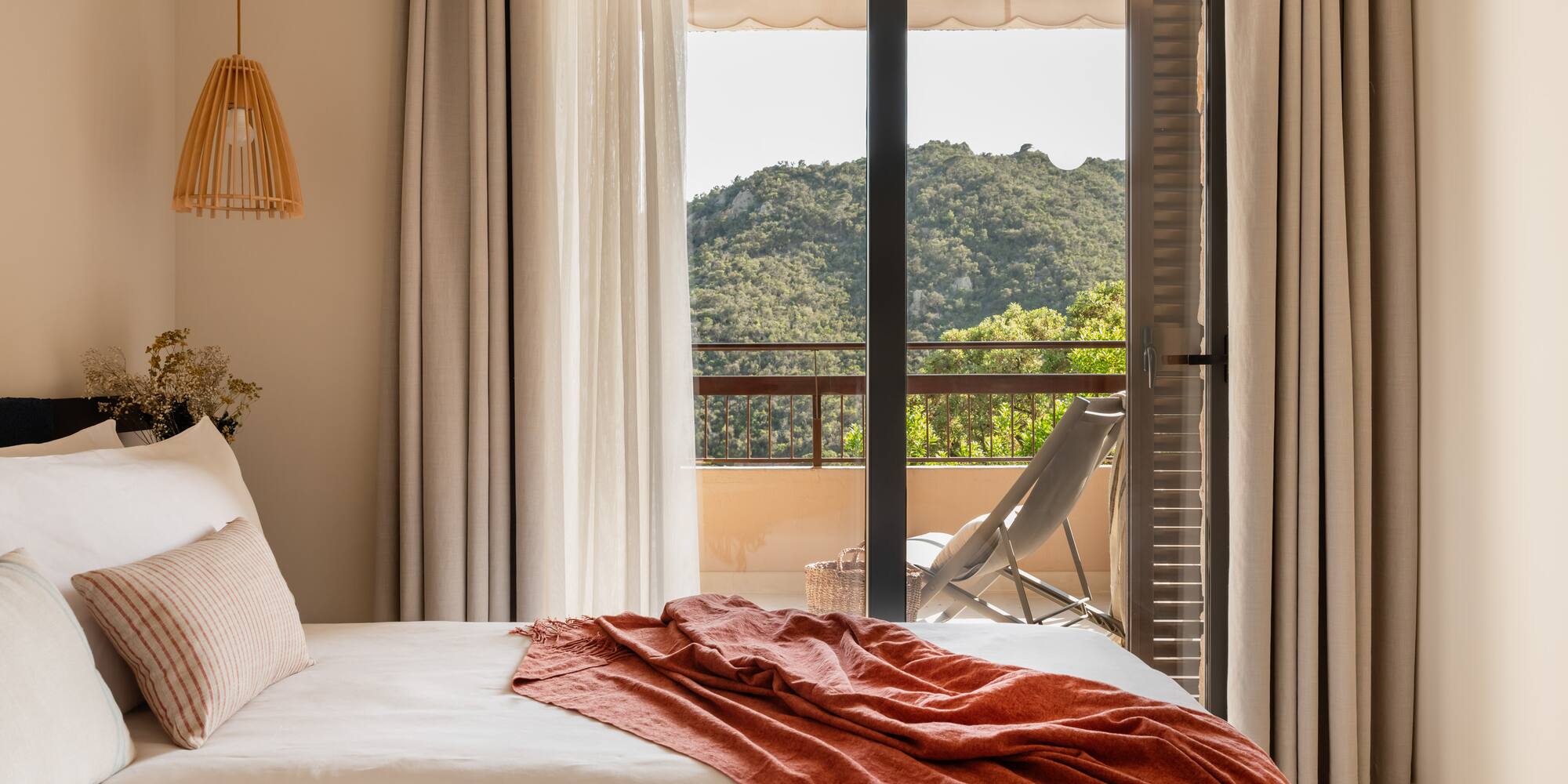 a bed with a red blanket and a chair outside