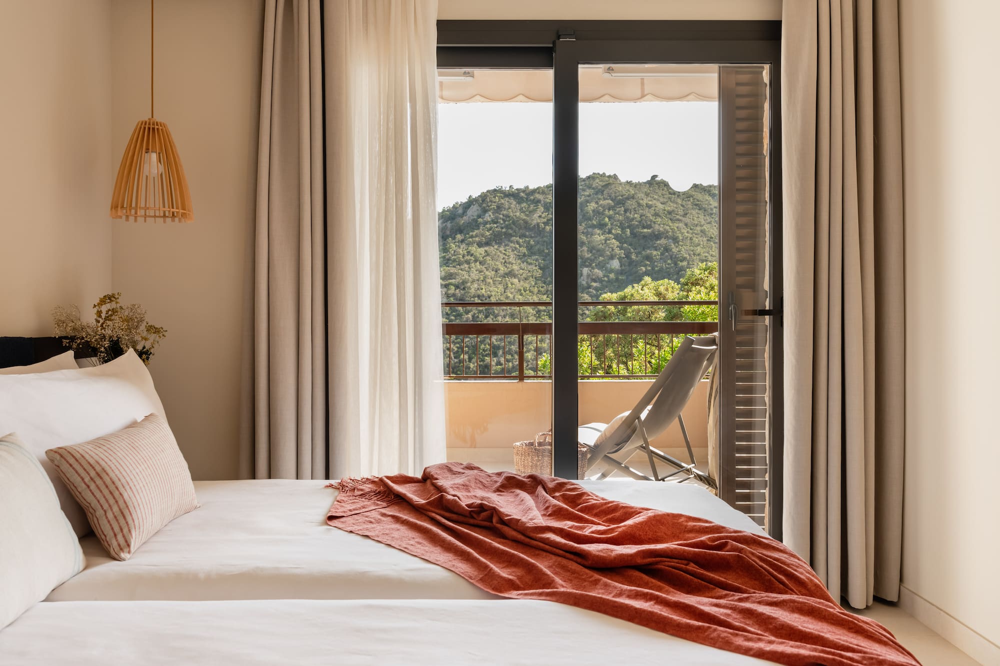 a bed with a red blanket and a chair outside