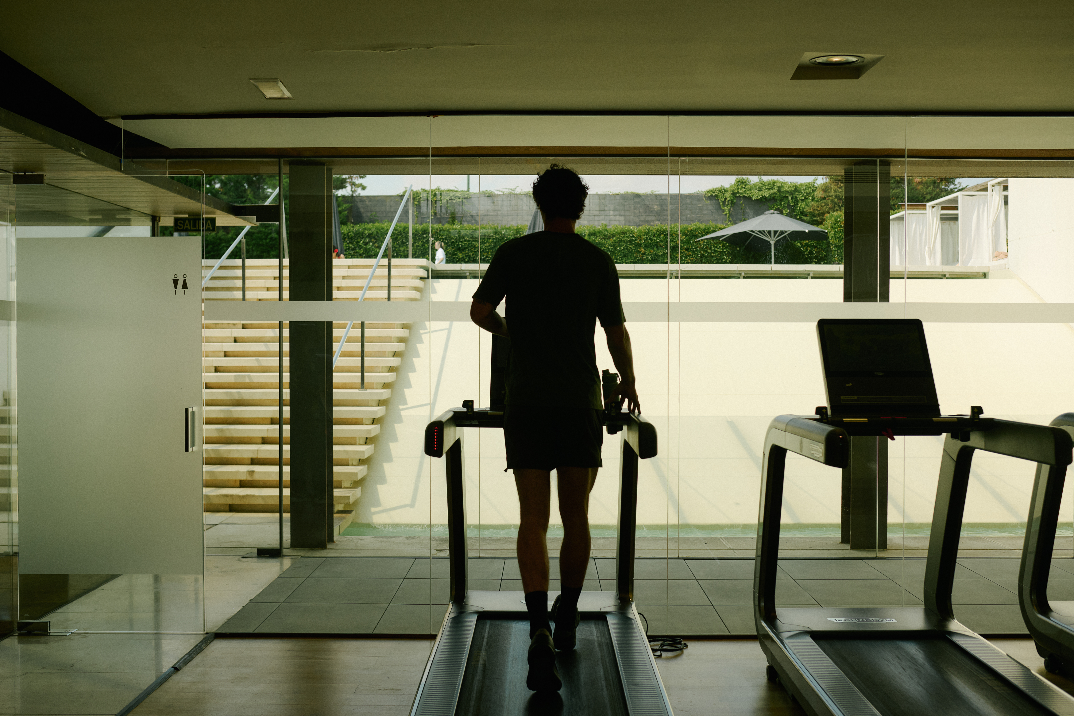 Person working out on treadmill in modern gym with resort view.