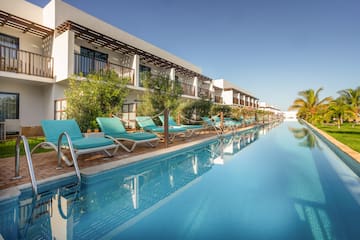 a pool with lounge chairs and trees in front of a building