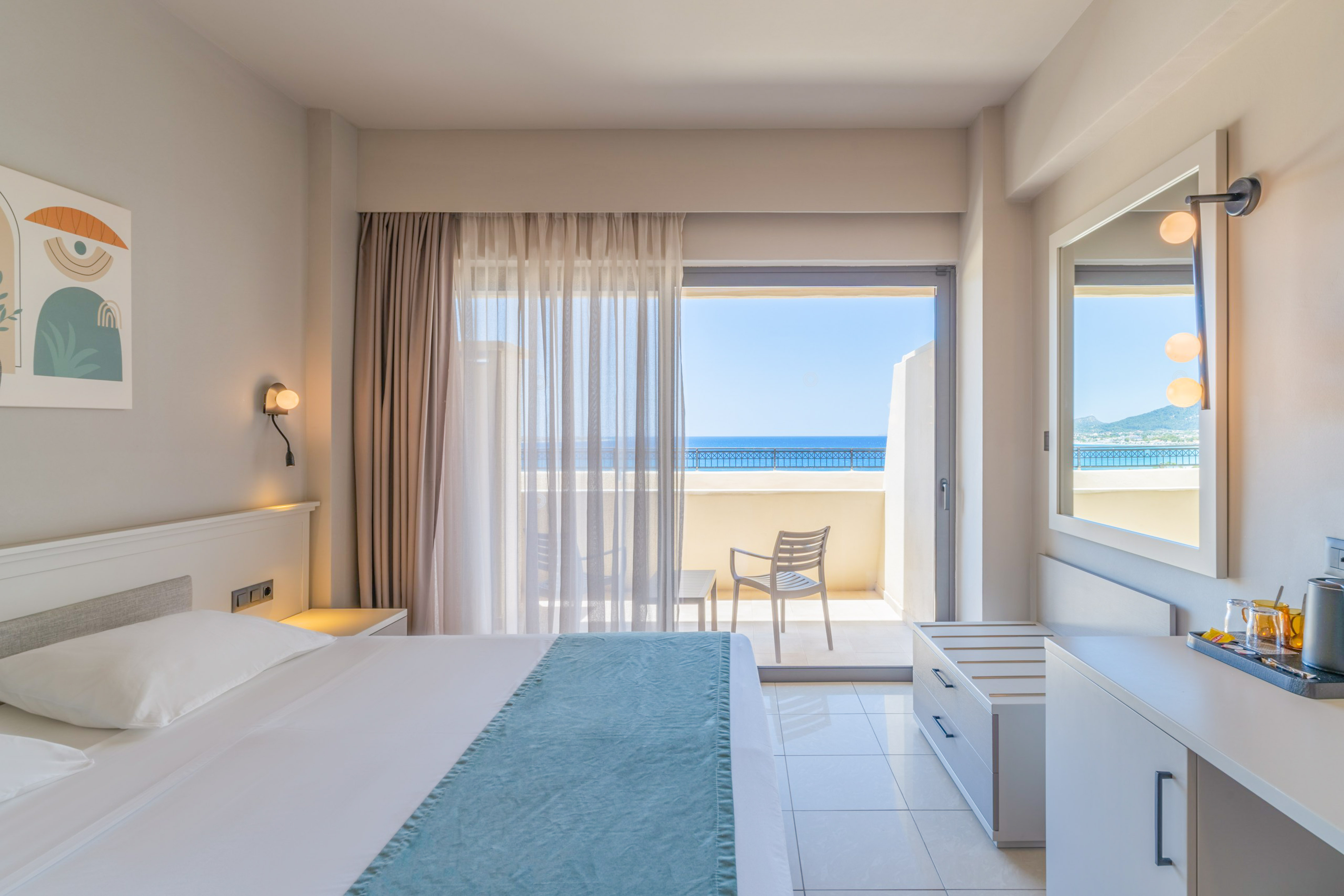 Bright hotel bedroom with sea view balcony and contemporary furnishings.