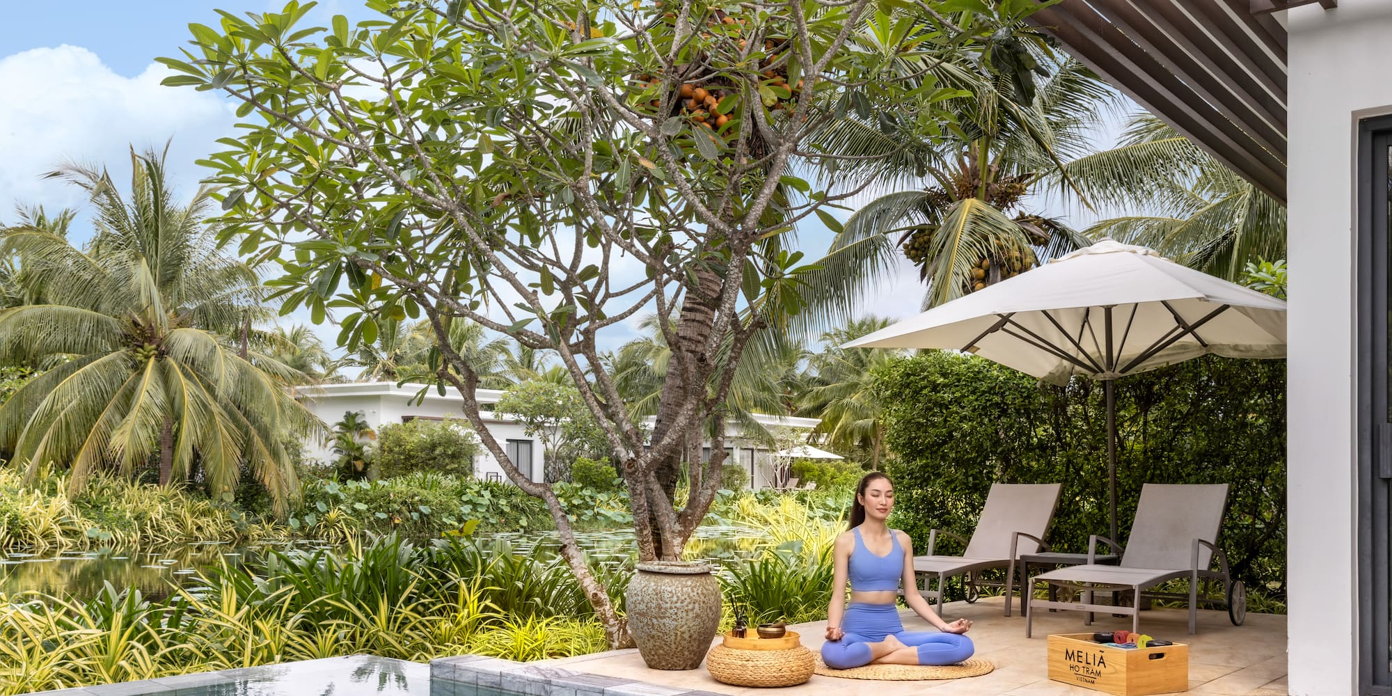Woman doing yoga meditation at a tropical resort pool, Melia Ho Tram.
