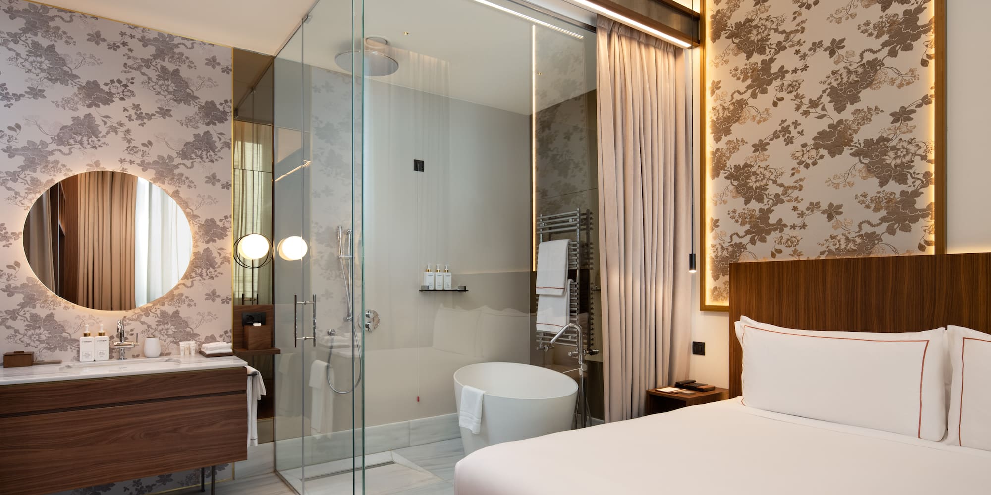 a room with a glass shower and a bed