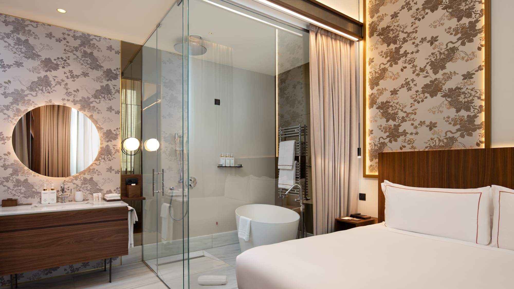 a room with a glass shower and a bed