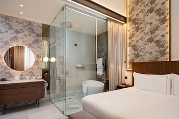 a room with a glass shower and a bed