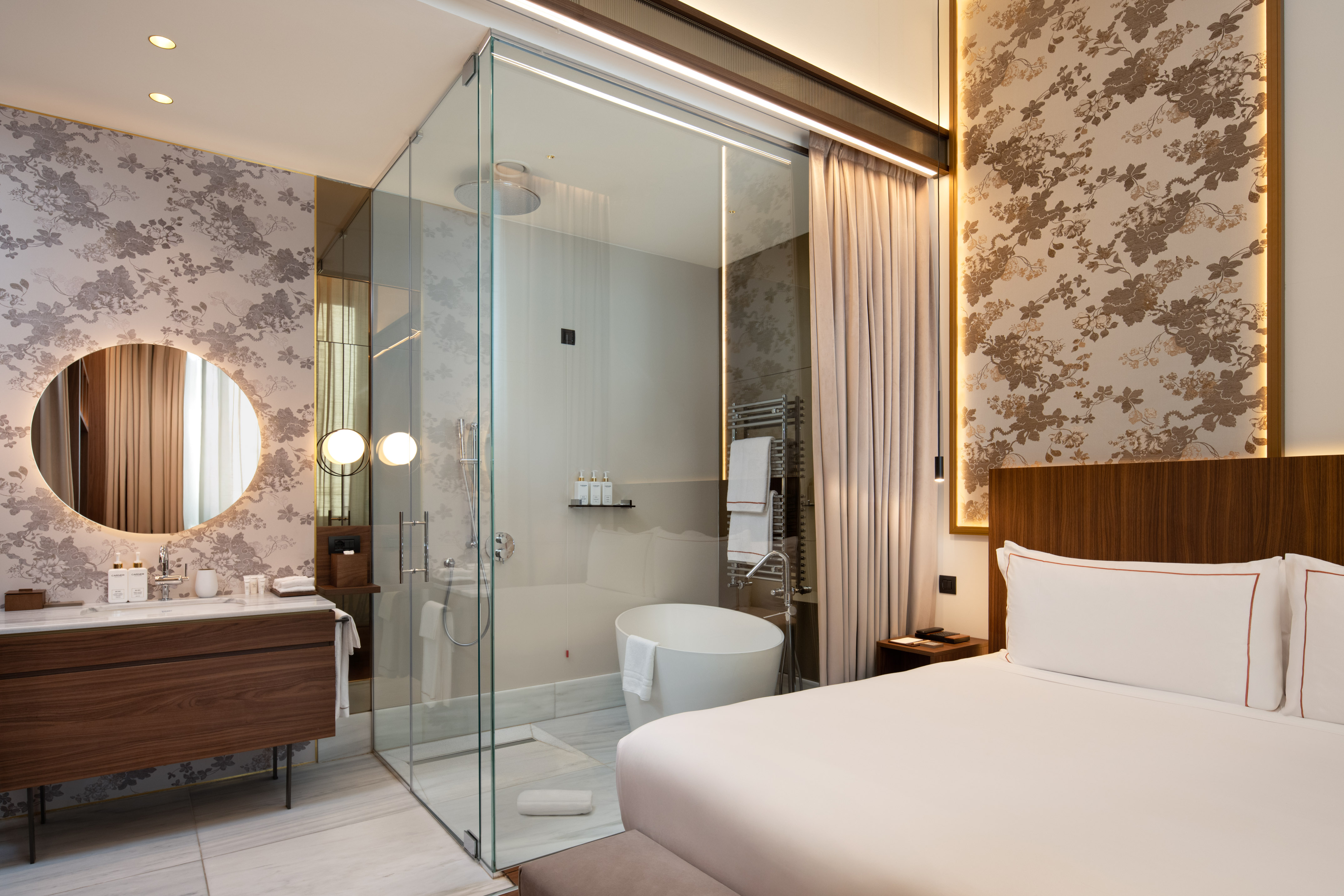 a room with a glass shower and a bed