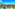 Tropical resort with pools, palm trees, and ocean view against blue sky.