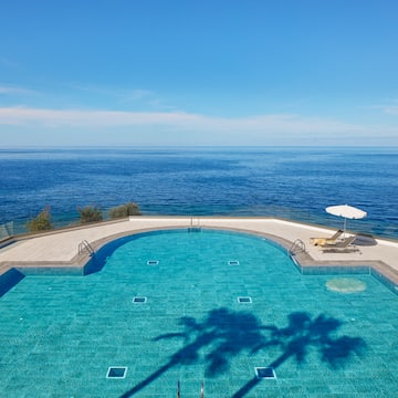 a swimming pool with a deck chair and umbrella overlooking the ocean