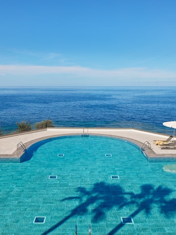 a swimming pool with a deck chair and umbrella overlooking the ocean