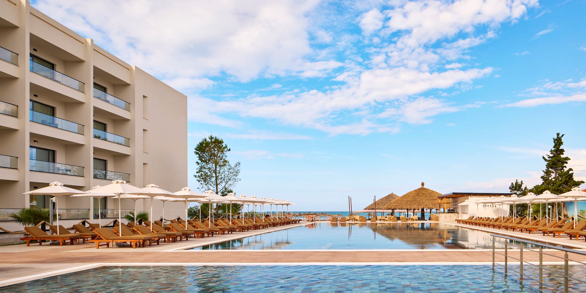 a pool with umbrellas and chairs in front of a building