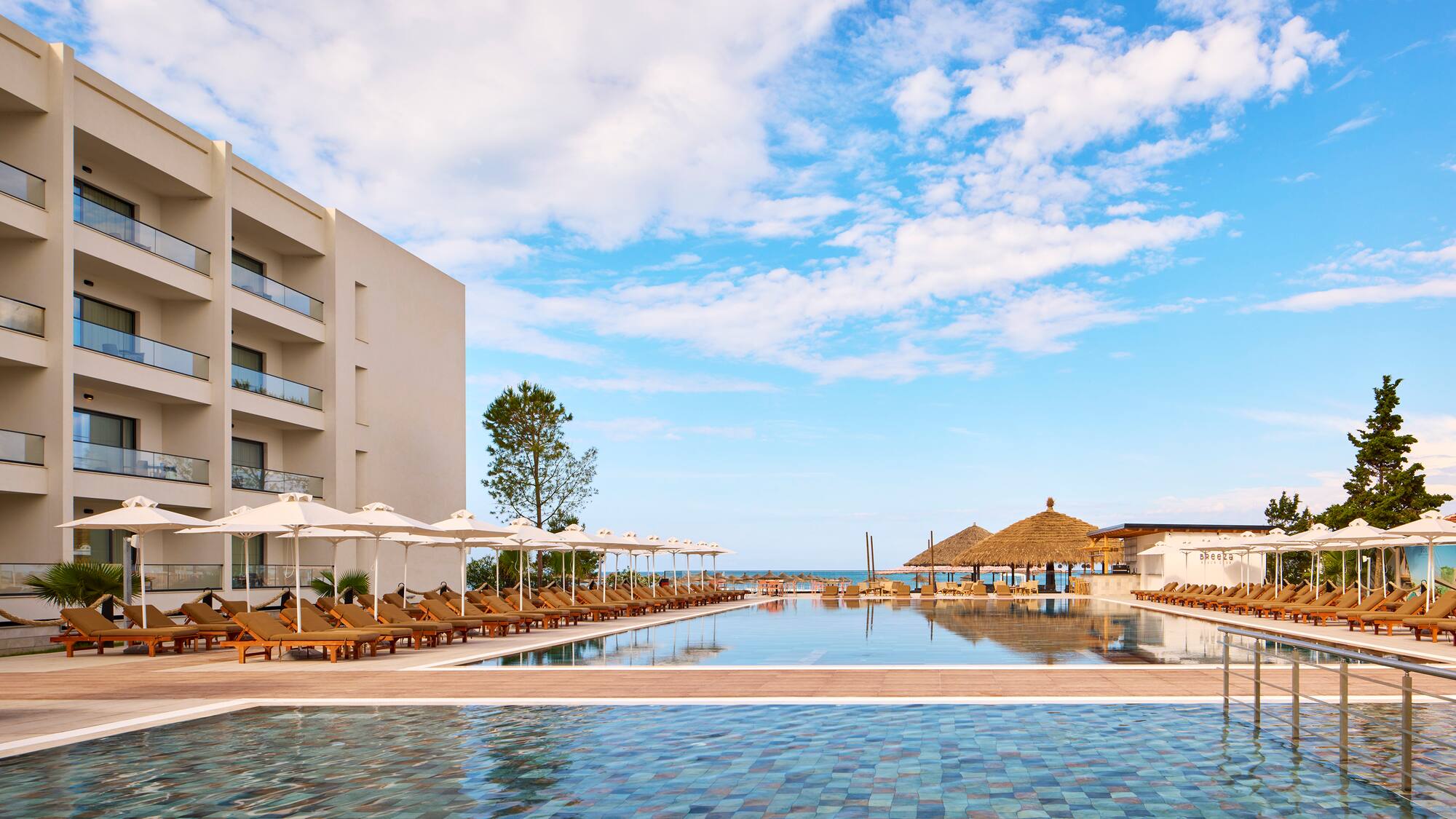 a pool with umbrellas and chairs in front of a building