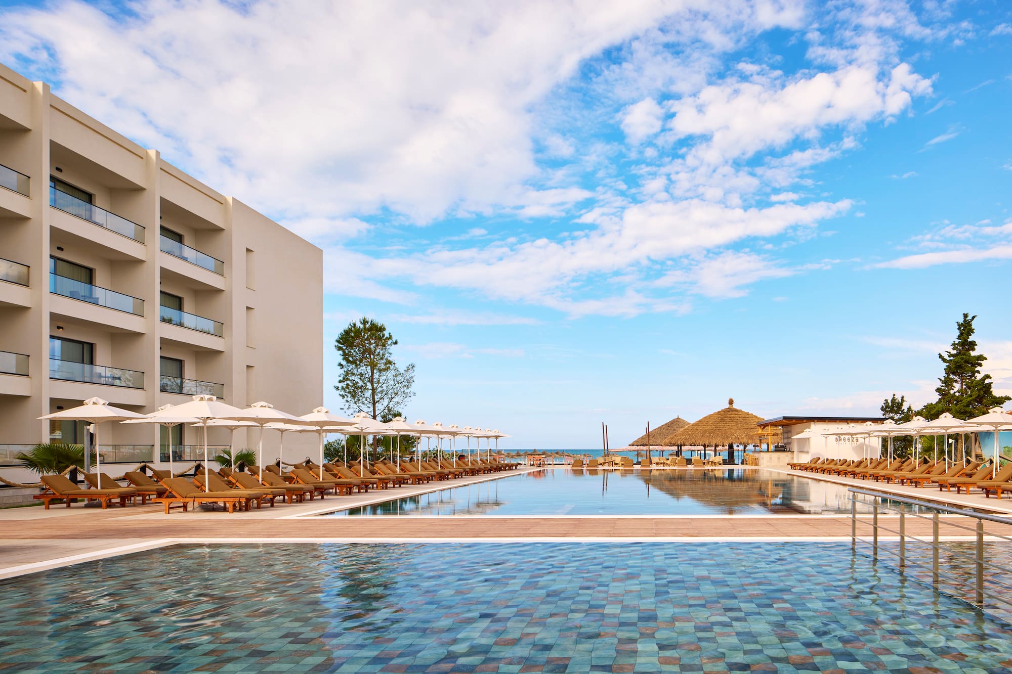 a pool with umbrellas and chairs in front of a building
