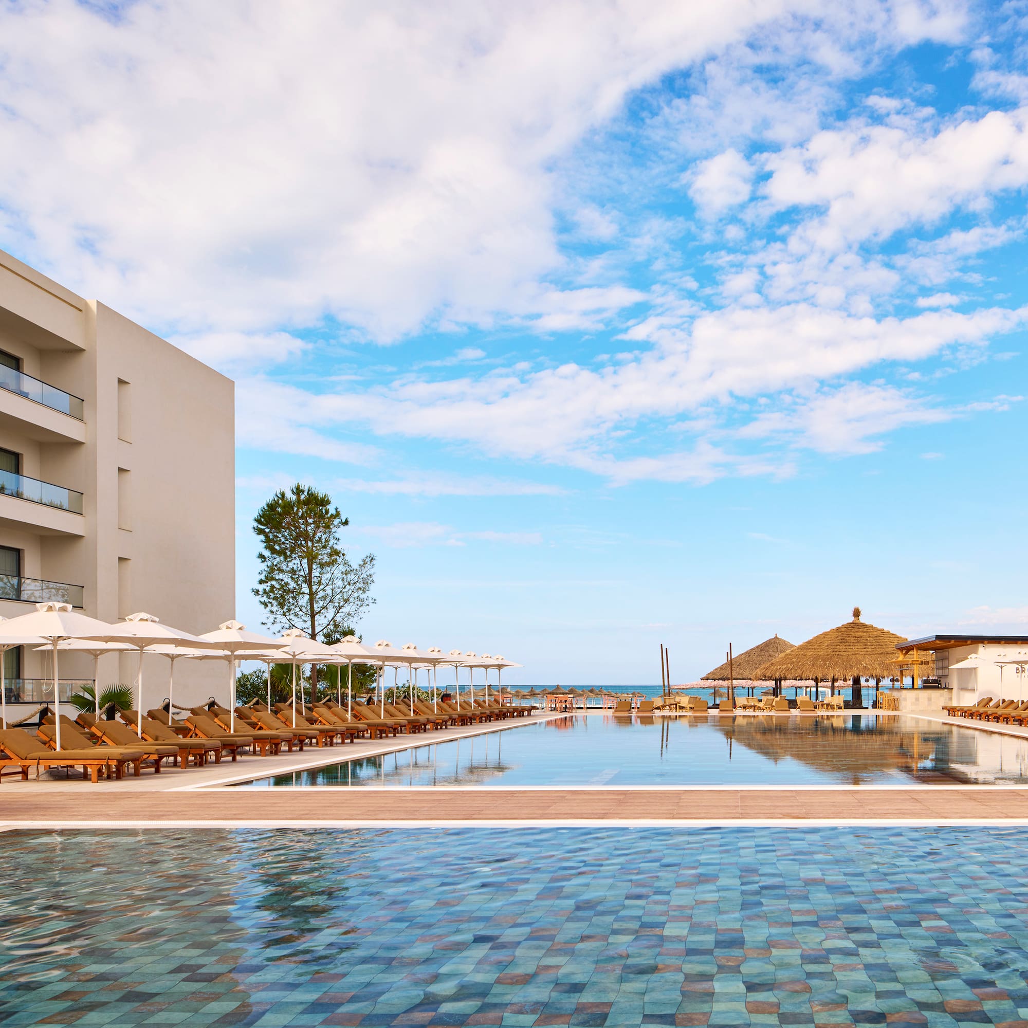 a pool with umbrellas and chairs in front of a building