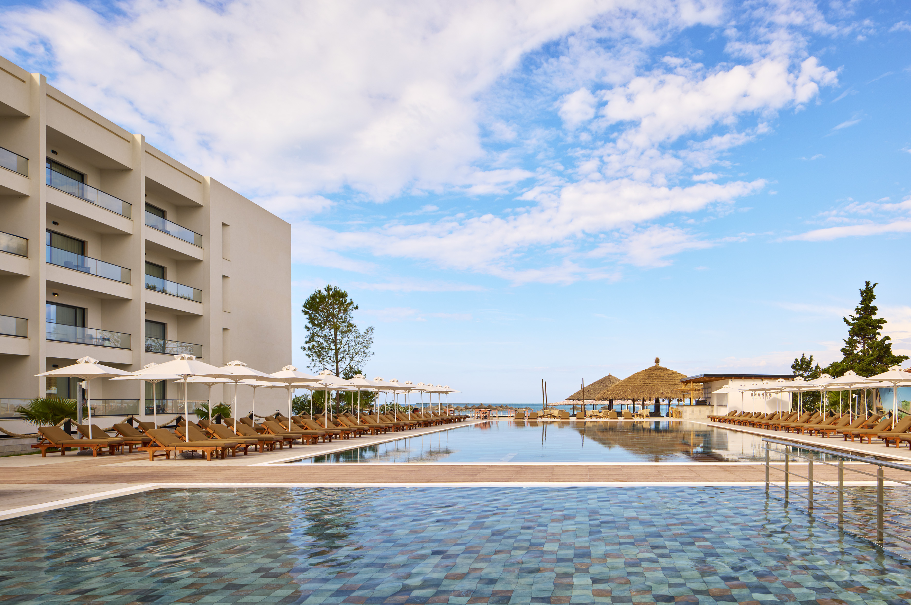 a pool with umbrellas and chairs in front of a building