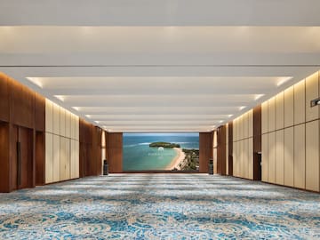 a large room with blue carpet and a view of the ocean