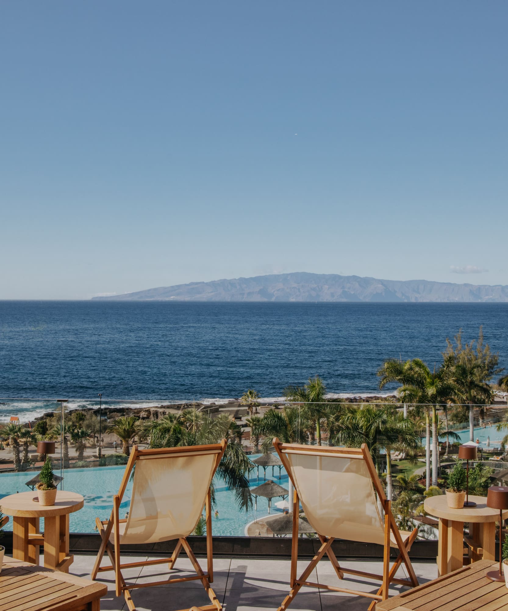 chairs and tables with chairs and a pool overlooking the ocean