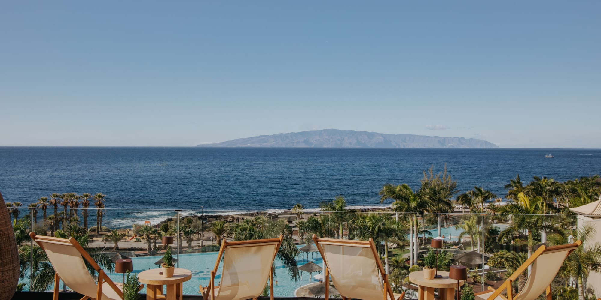 chairs and tables with chairs and a pool overlooking the ocean